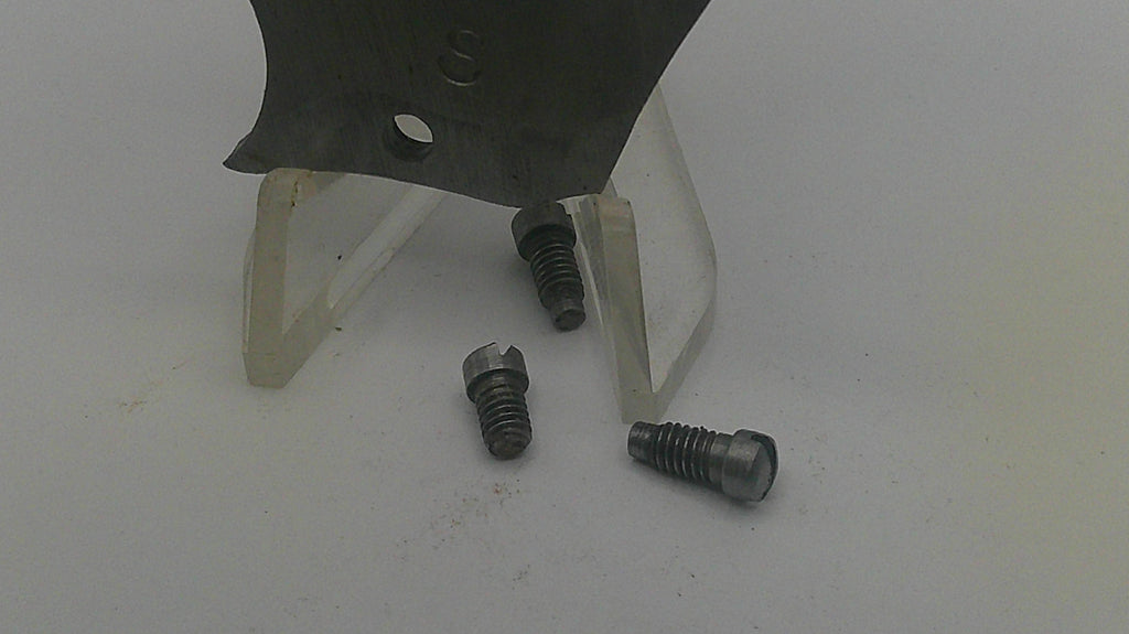 Three screws on a white surface with a metal object in the background