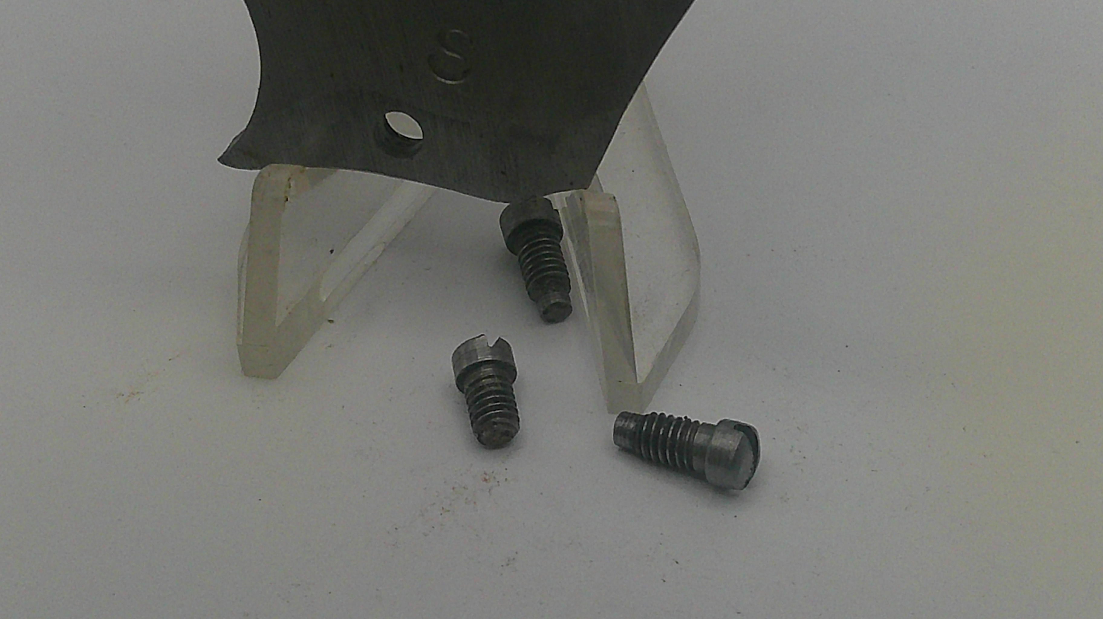 Three screws on a white surface with a metal object in the background
