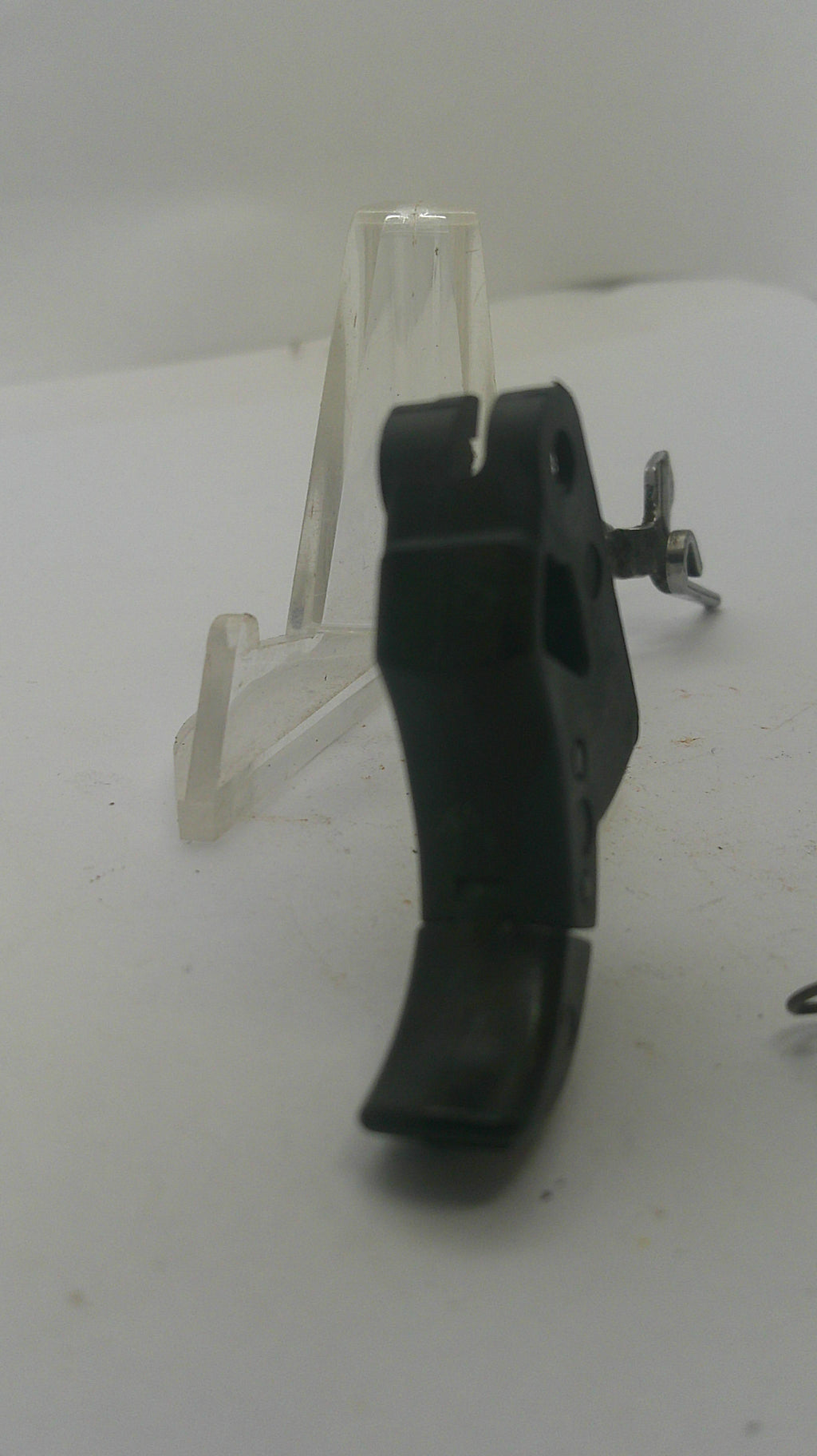 A black plastic trigger assembly with a clear plastic clip and a small silver wing nut, shown on a plain white background.