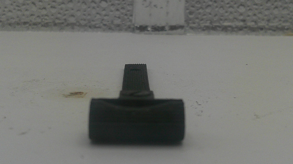 A close-up shot of a black plastic razor handle and head, resting on a light gray textured surface.