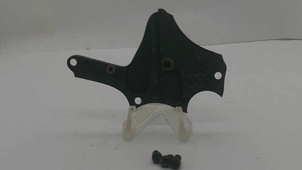 A black plastic mounting bracket or hardware piece displayed on a clear plastic stand, with a few small black screws placed below it on a plain white surface.