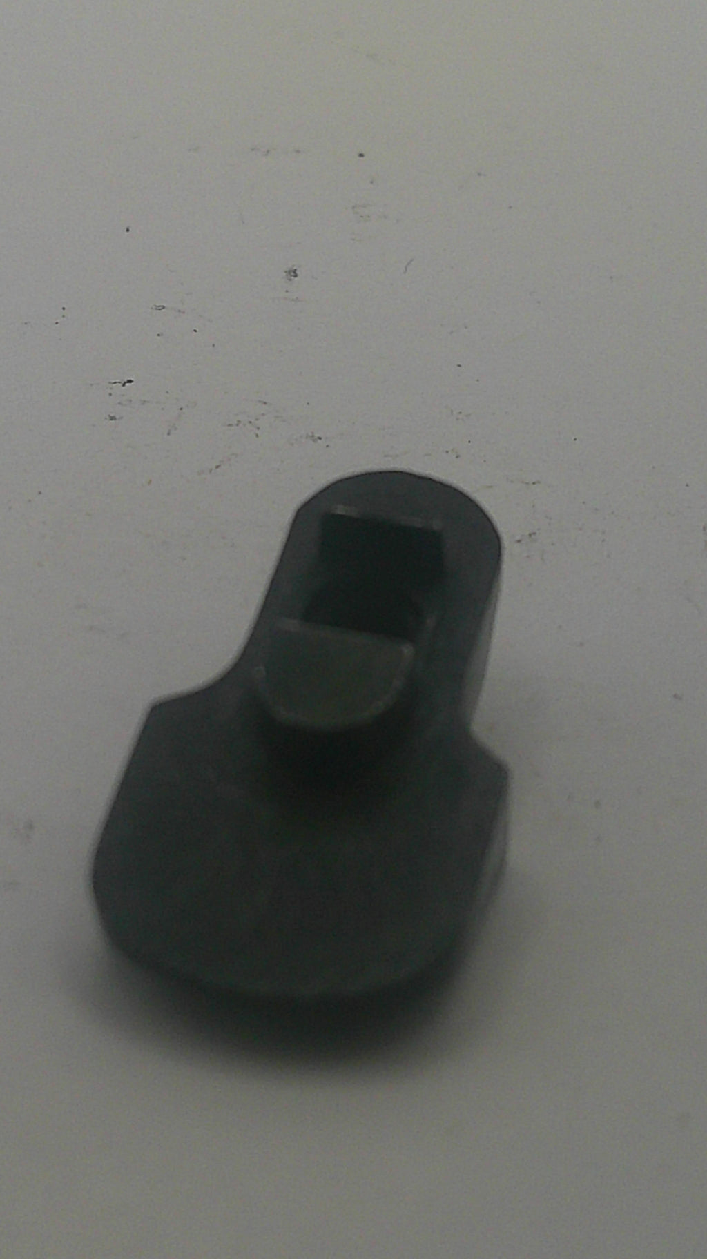 A small black plastic or rubber hardware piece with a rectangular slot, photographed on a plain light gray surface.