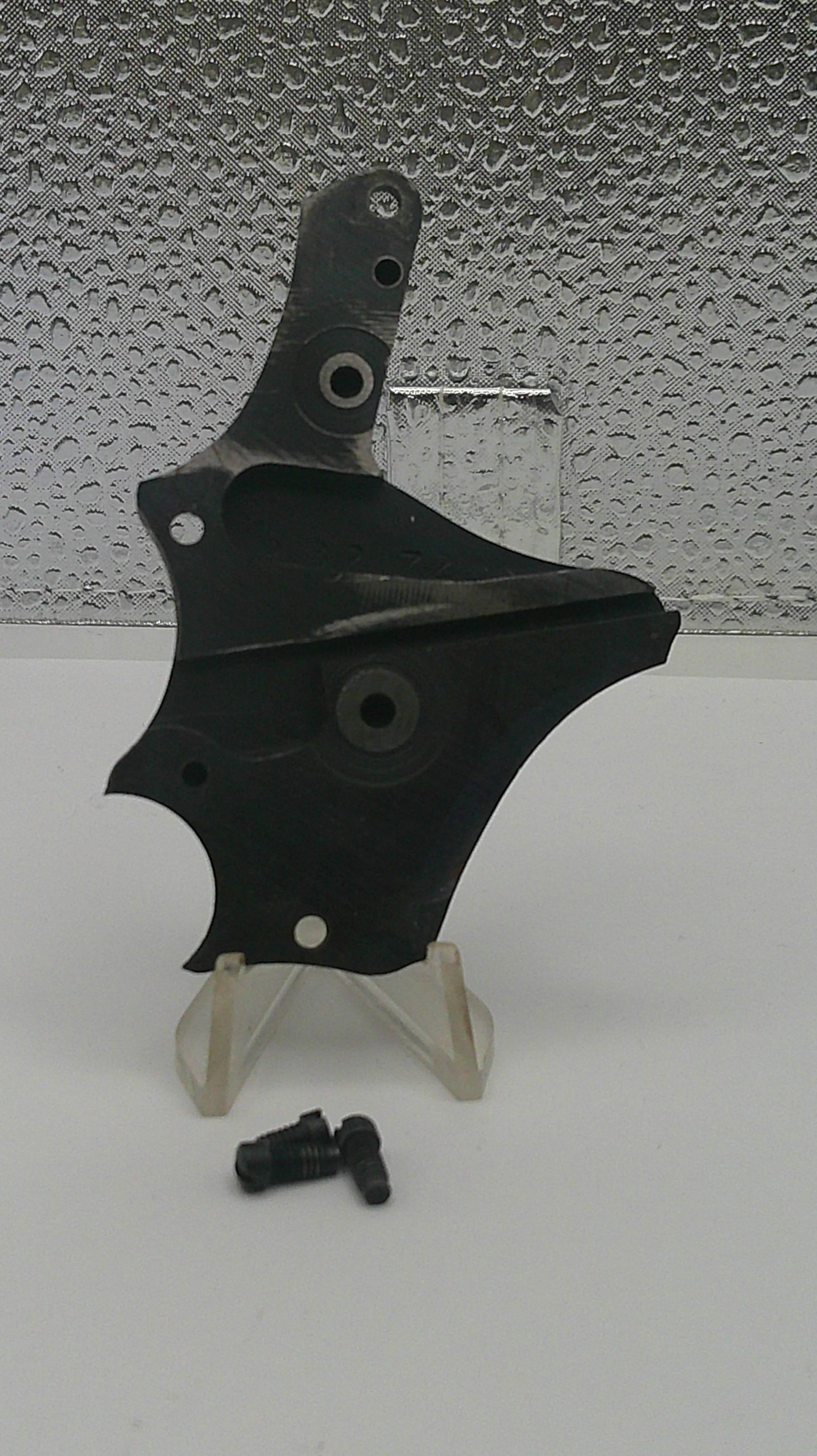 Black metal bracket with screws on a textured gray surface