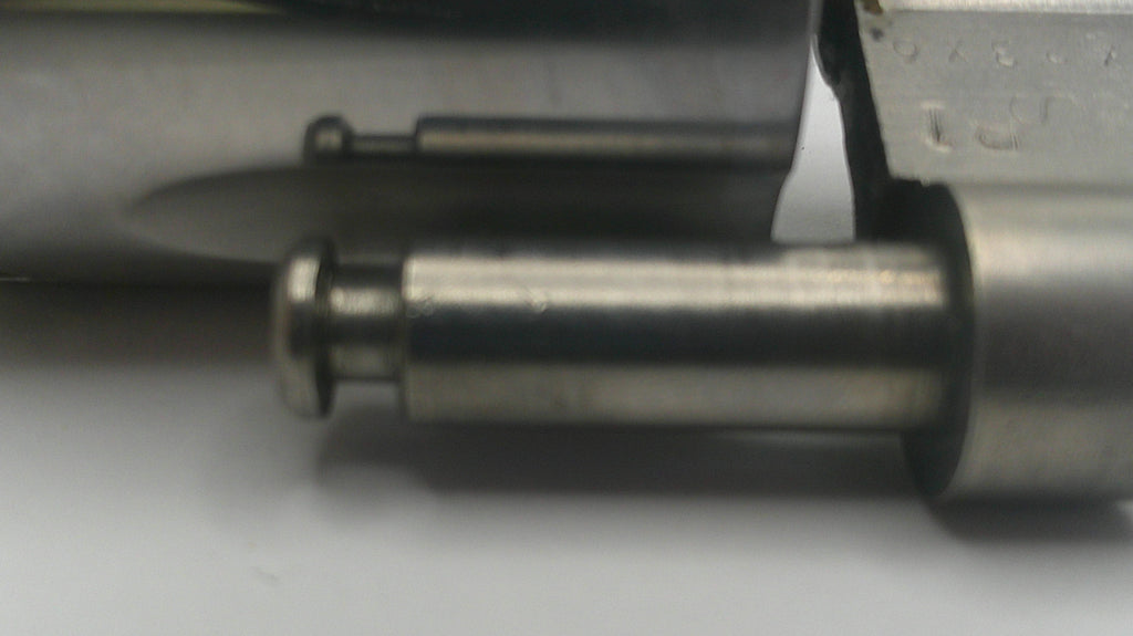 Close-up of a metallic object with a pointed tip on a gray background