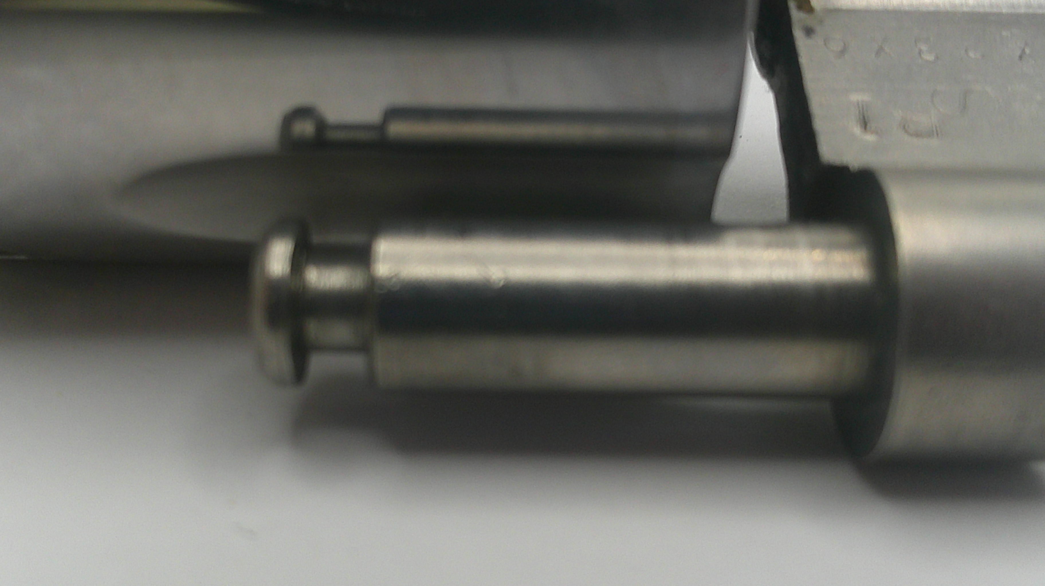 Close-up of a metallic object with a pointed tip on a gray background