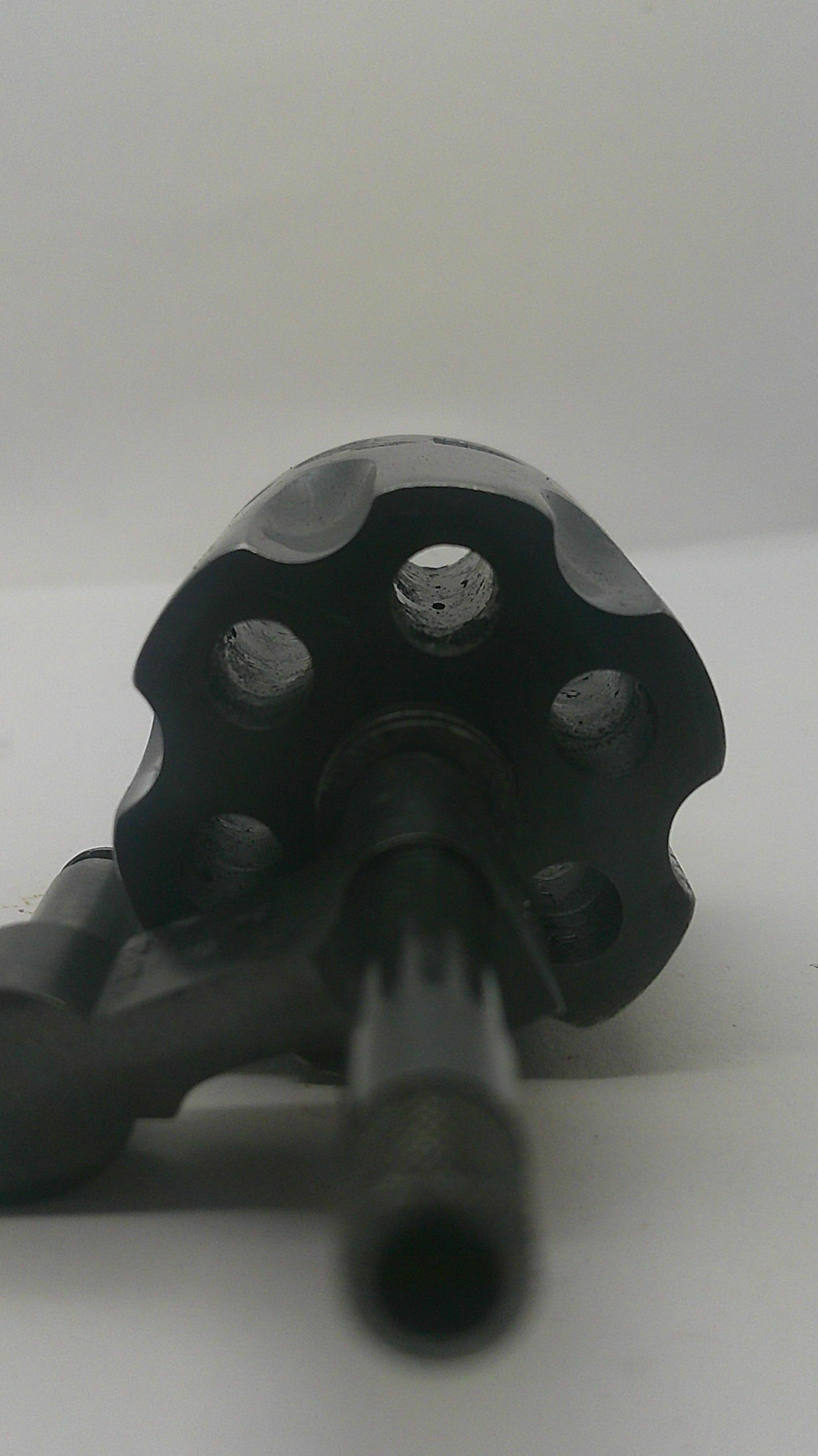 A close-up shot of a black metal revolver grip and barrel shroud on a white background.