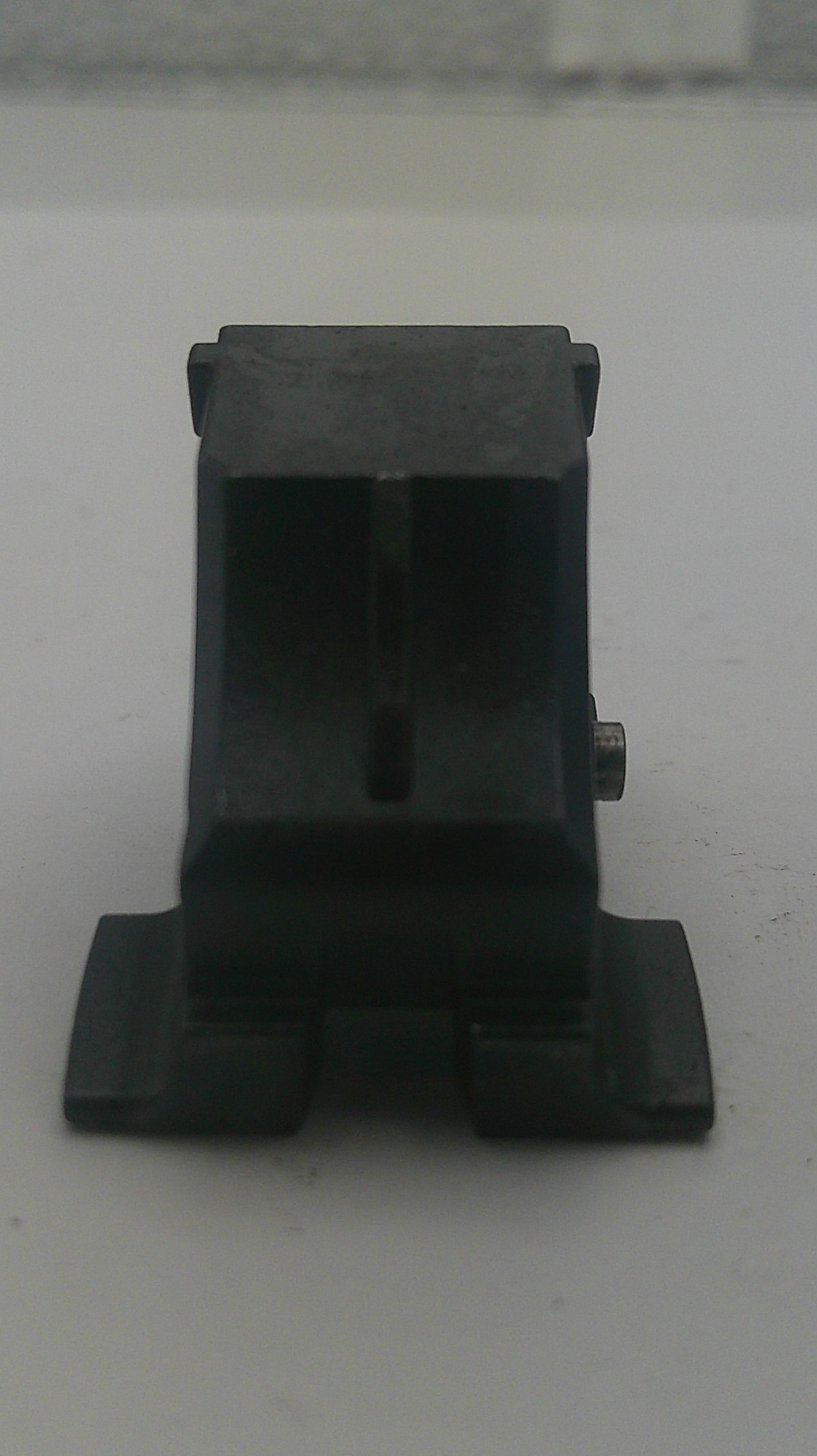 A black plastic mounting bracket or clip with a small silver screw visible at the bottom center, photographed against a plain light gray background.