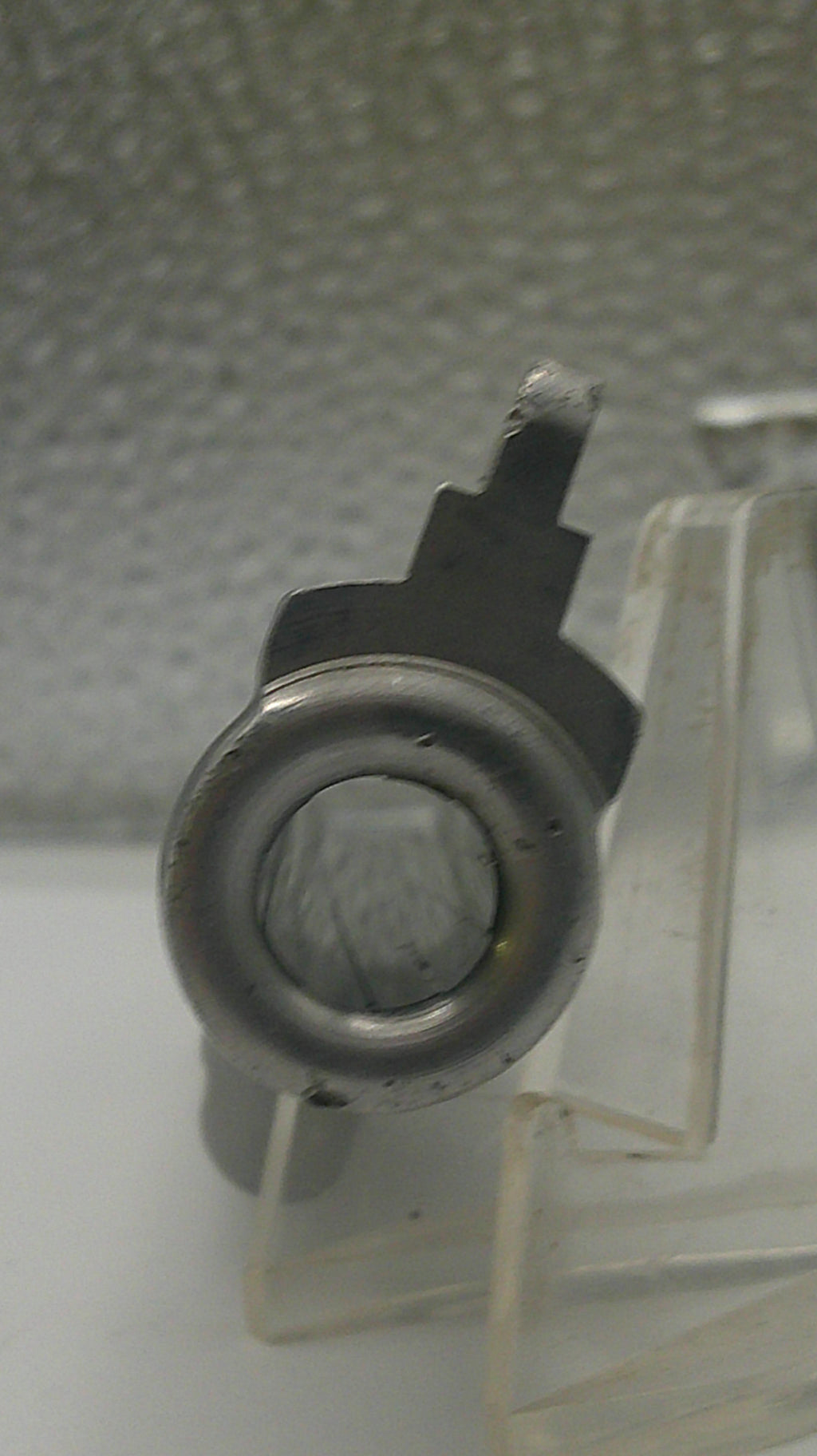 Mechanical component on a clear stand against a textured wall