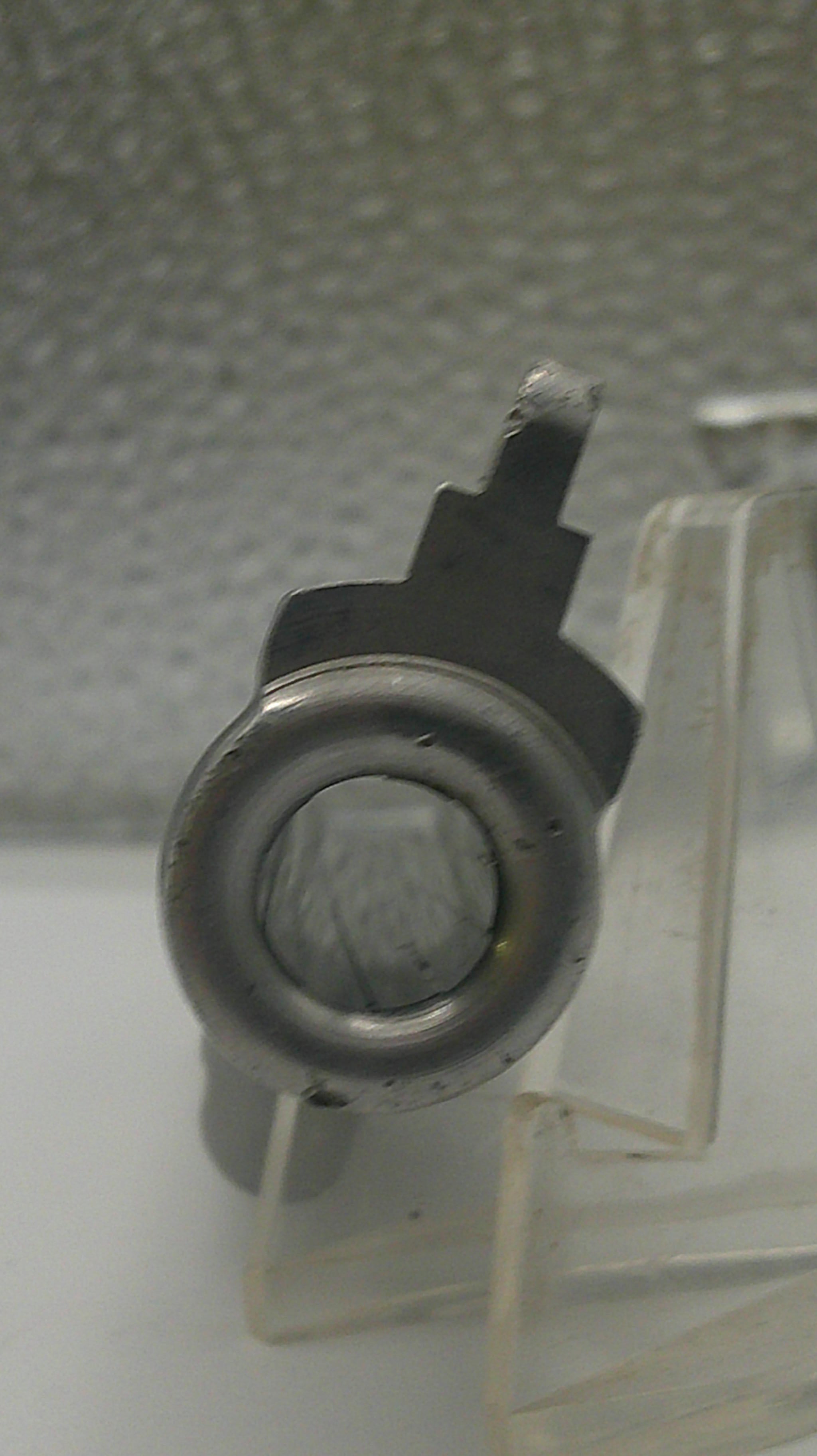 Mechanical component on a clear stand against a textured wall