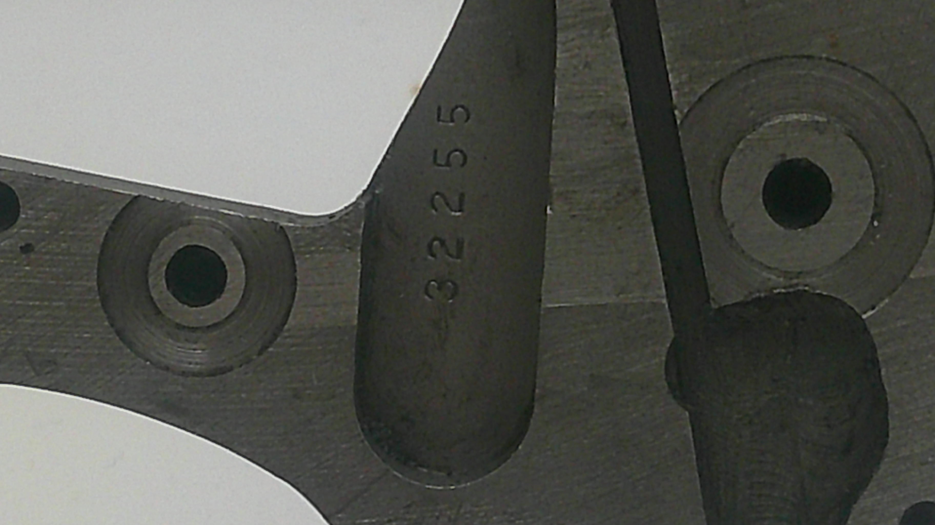 Metal component with embossed number '32255' on a blurred background