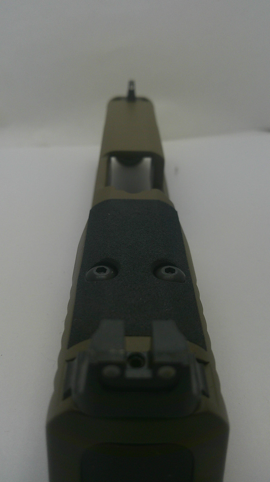 Close-up of a tactical firearm receiver and handguard section in olive drab and black, photographed against a plain light background.