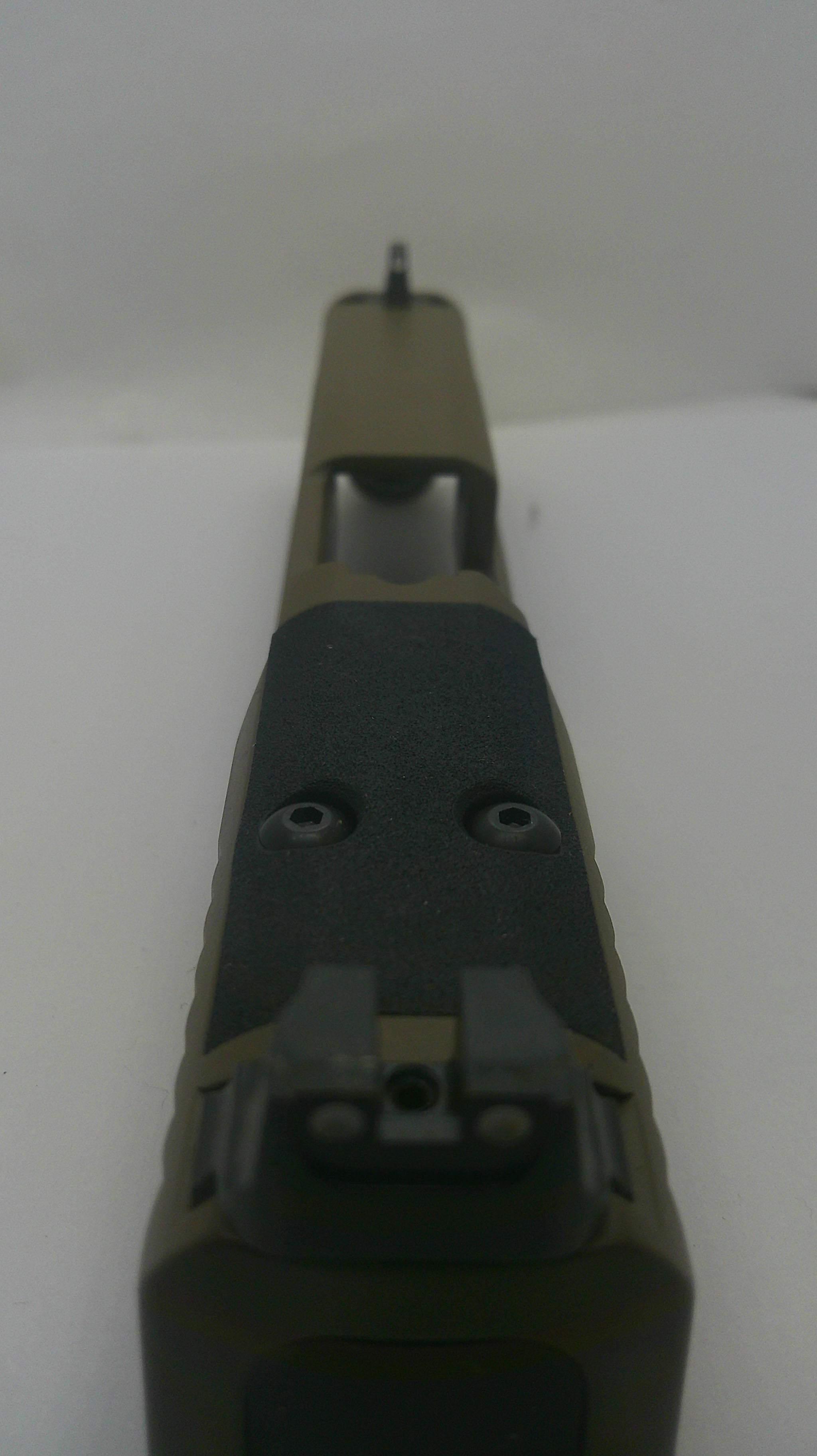 Close-up of a tactical firearm receiver and handguard section in olive drab and black, photographed against a plain light background.