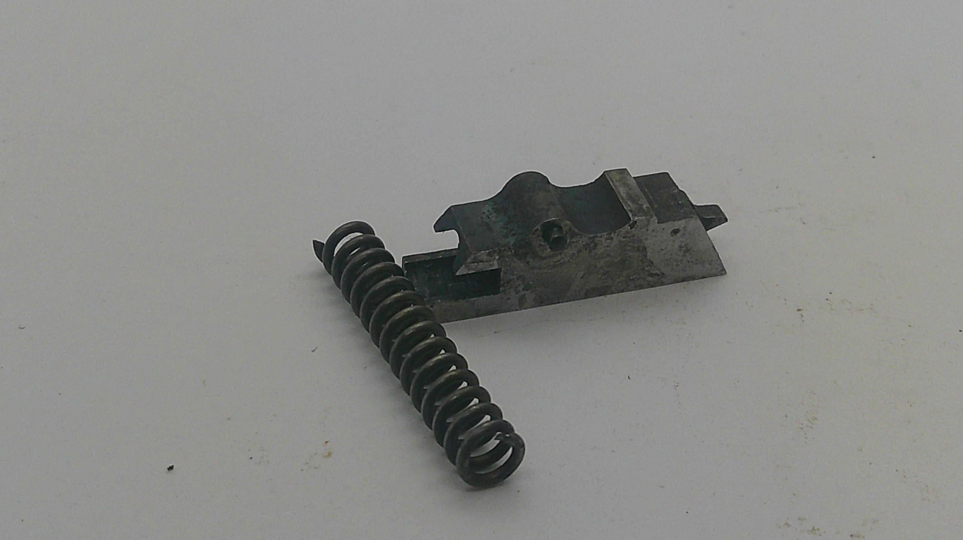 A small mechanical replacement part consisting of a dark metal spring and a matching metal bracket, shown on a plain off-white background.