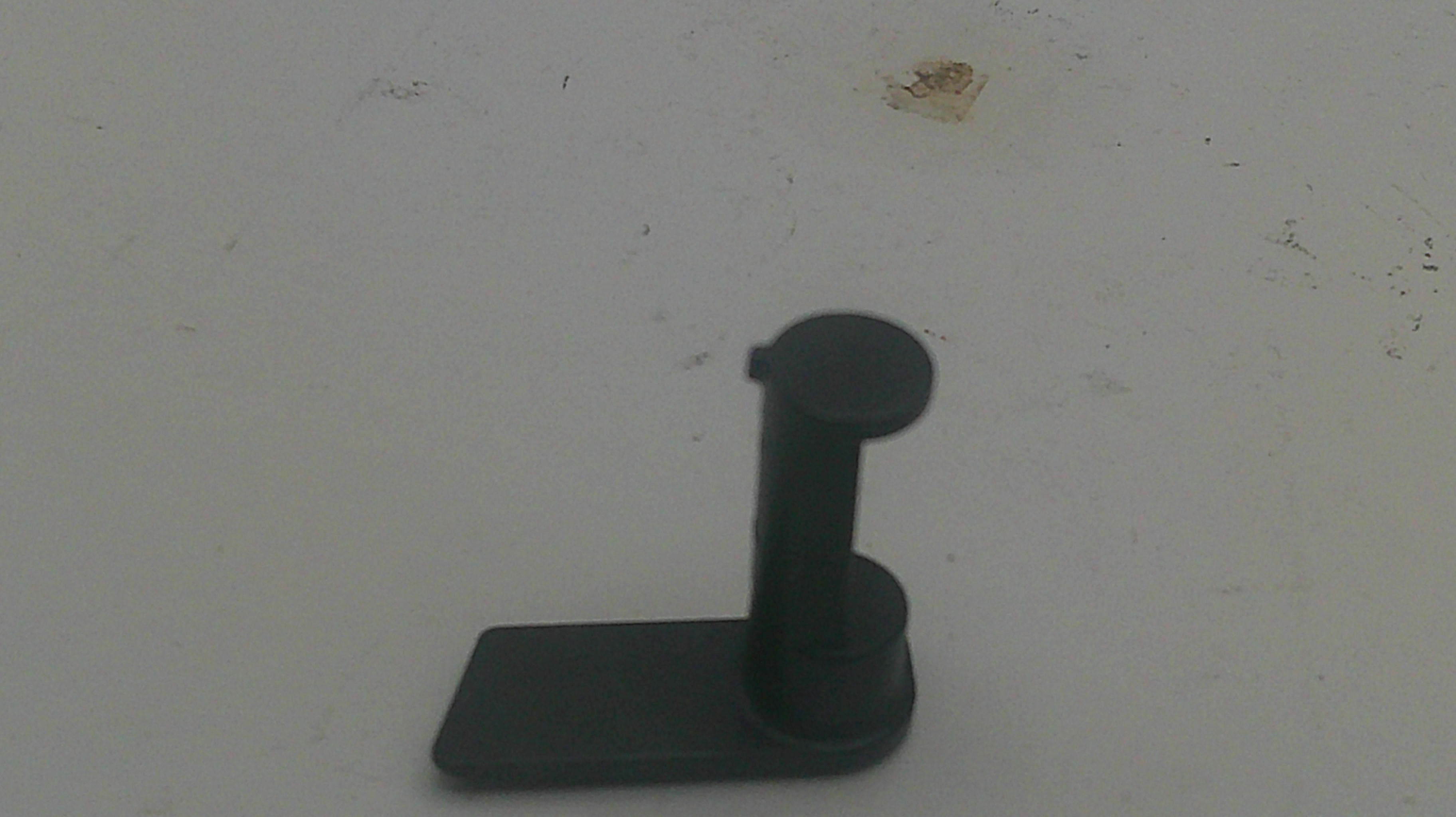 A small black plastic mounting bracket or stand with a flat rectangular base and a vertical cylindrical post, shown on a plain off-white surface.