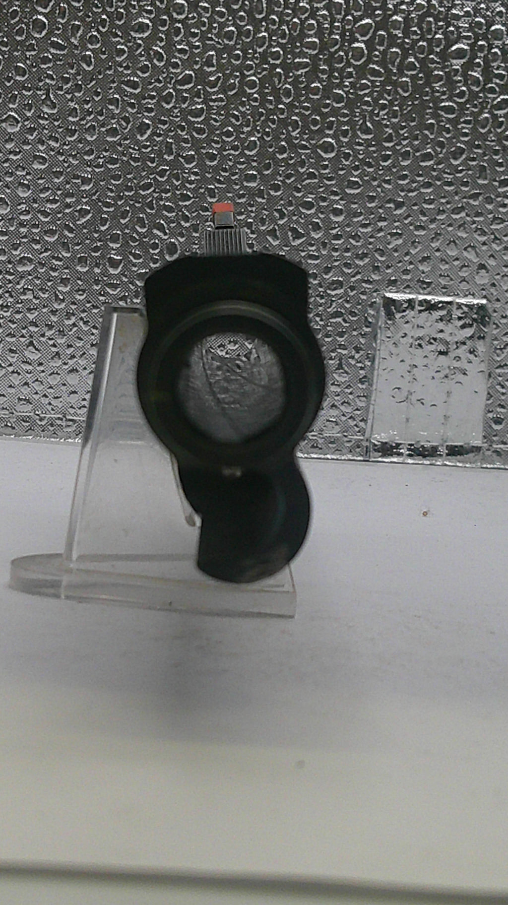 Black shower head on a textured wall with water droplets