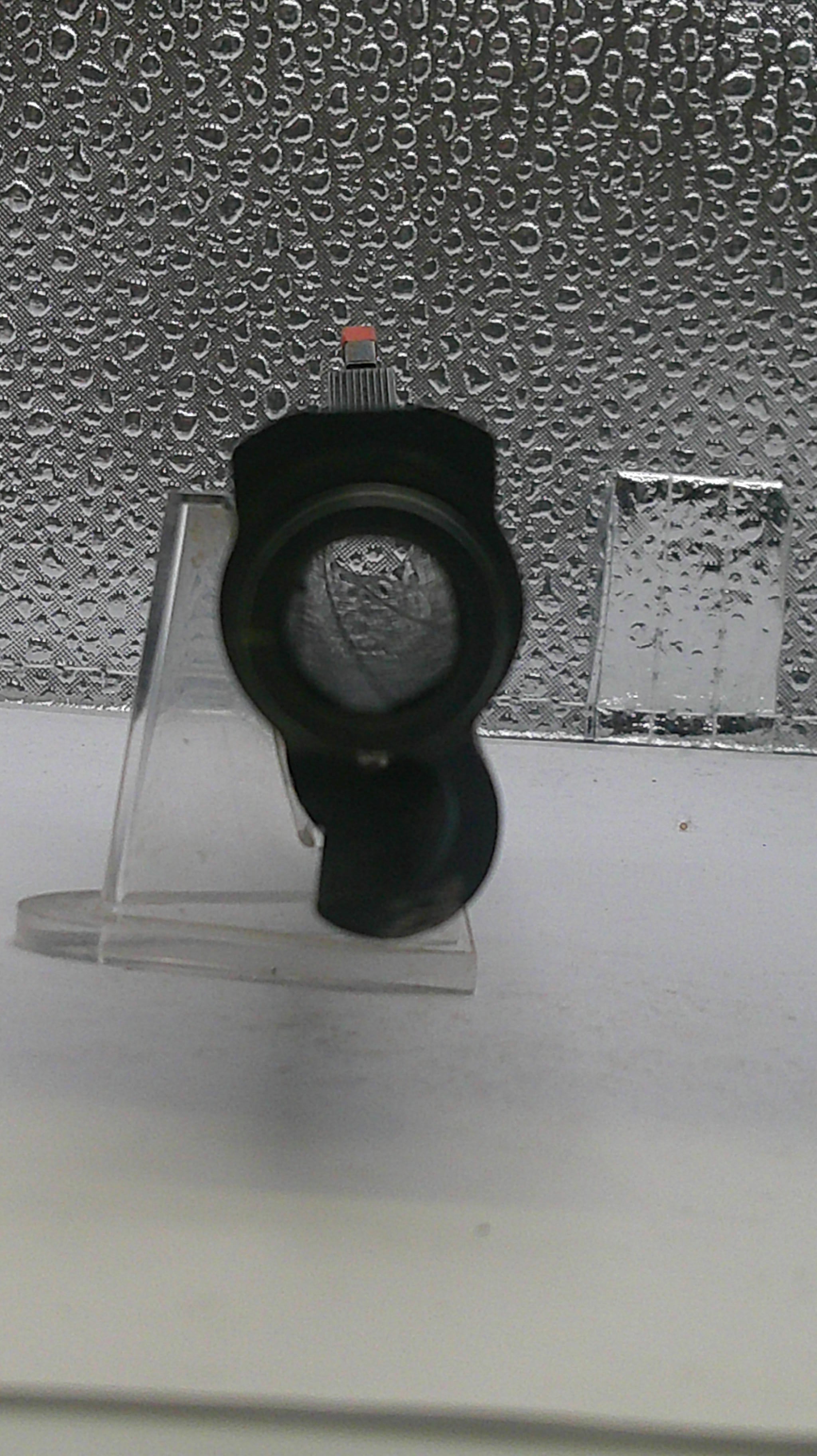 Black shower head on a textured wall with water droplets