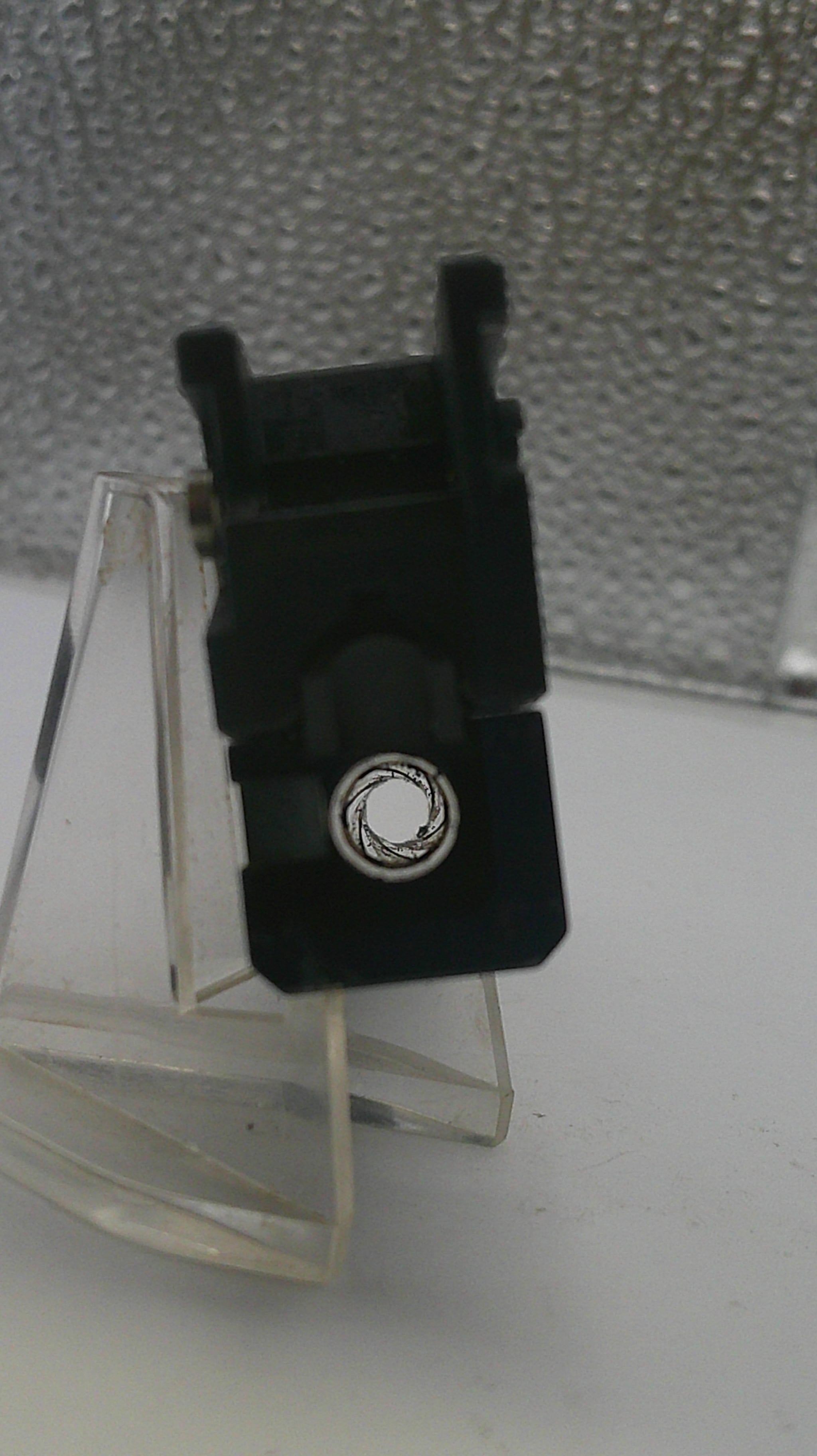 Close-up of a black vinyl record player needle on a clear stand.
