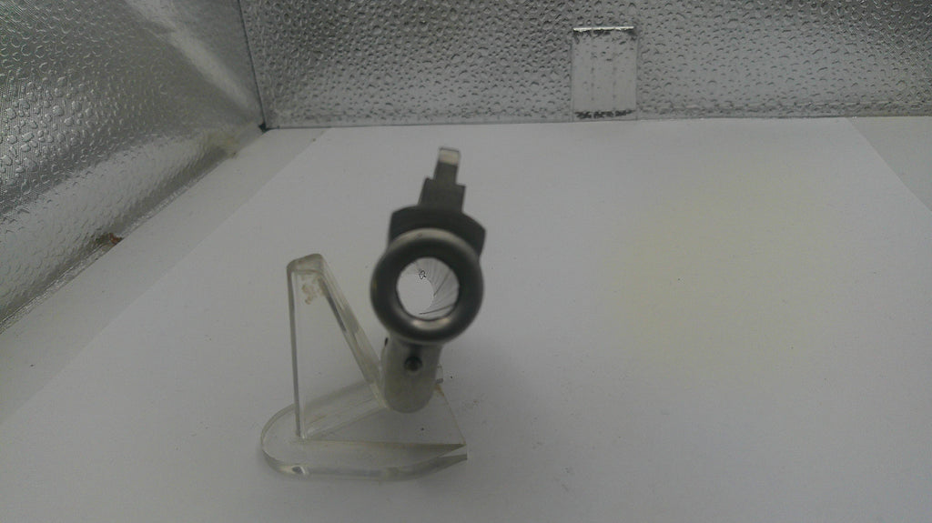Small mechanical component on a stand against a textured white background