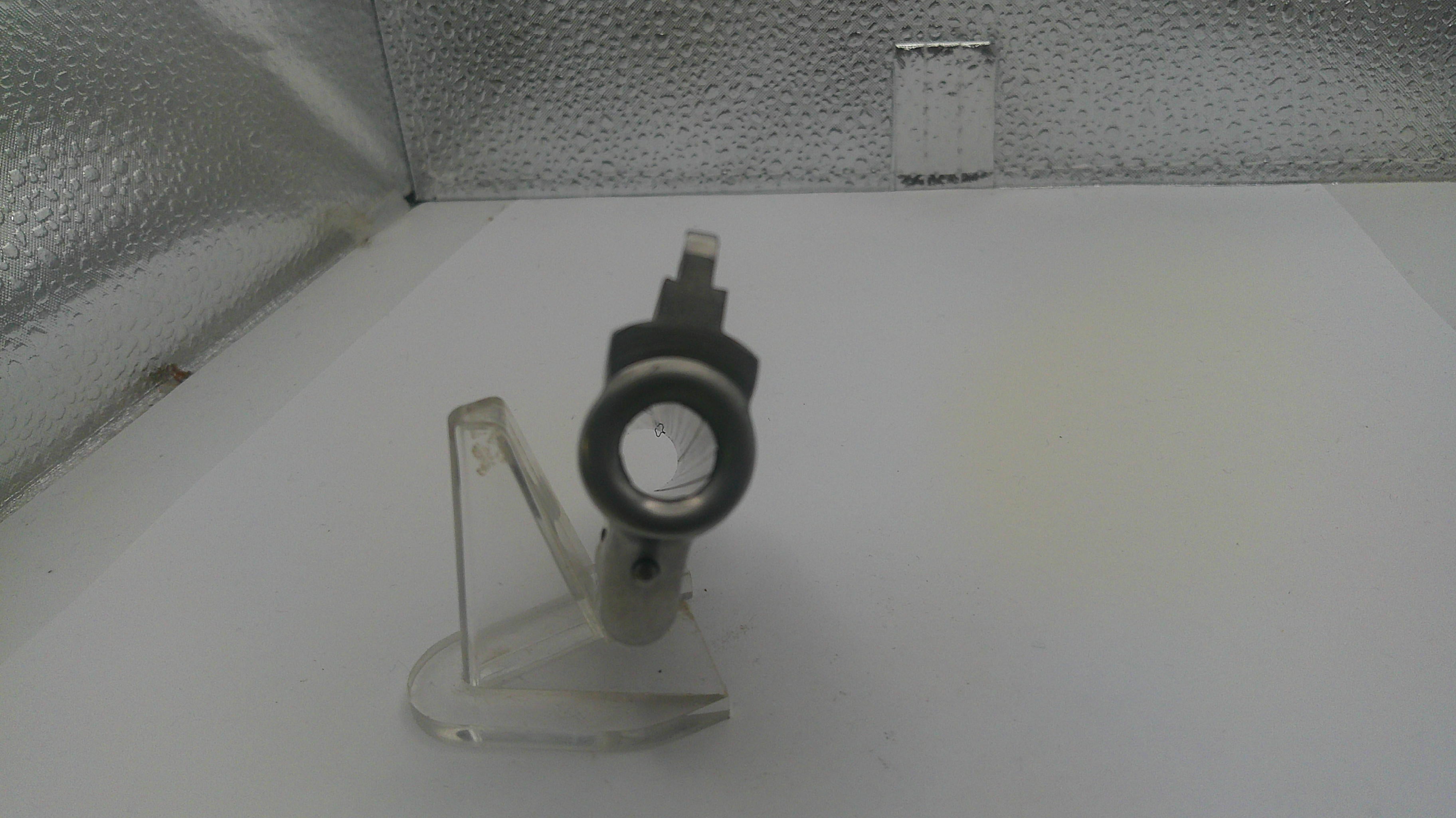 Small mechanical component on a stand against a textured white background