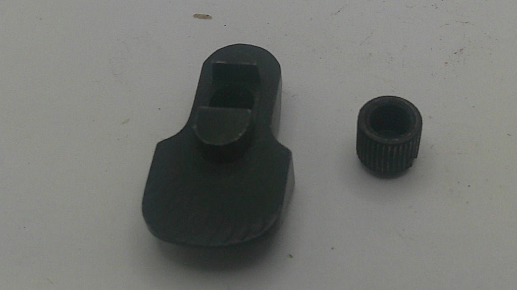 A black plastic rifle sight adjustment piece shown next to a matching black threaded cap on a plain light gray surface.