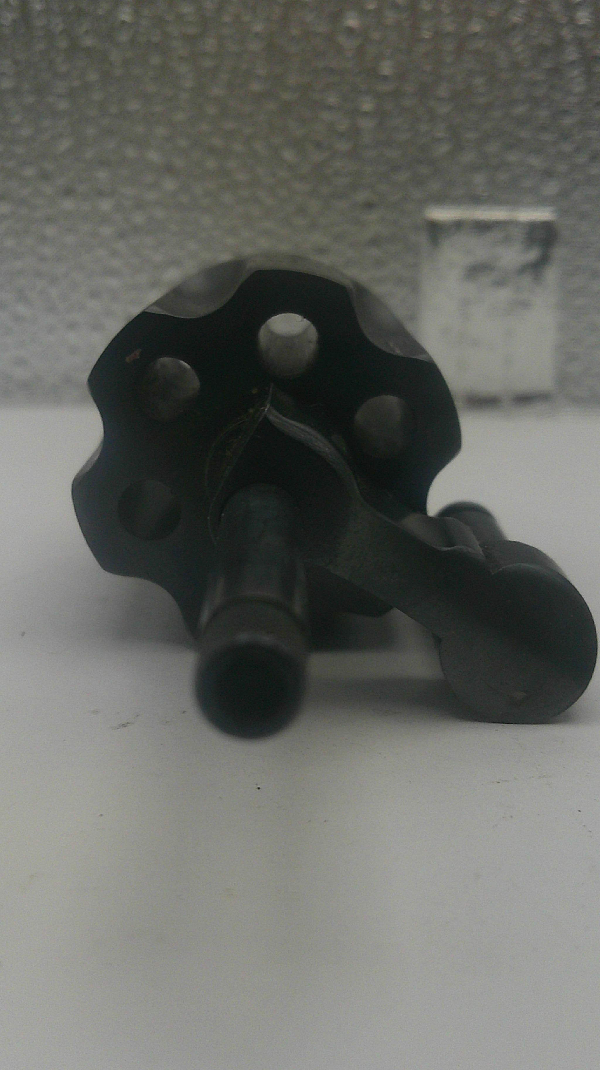 A close-up of a black metal revolver cylinder and barrel assembly, photographed against a plain light background.