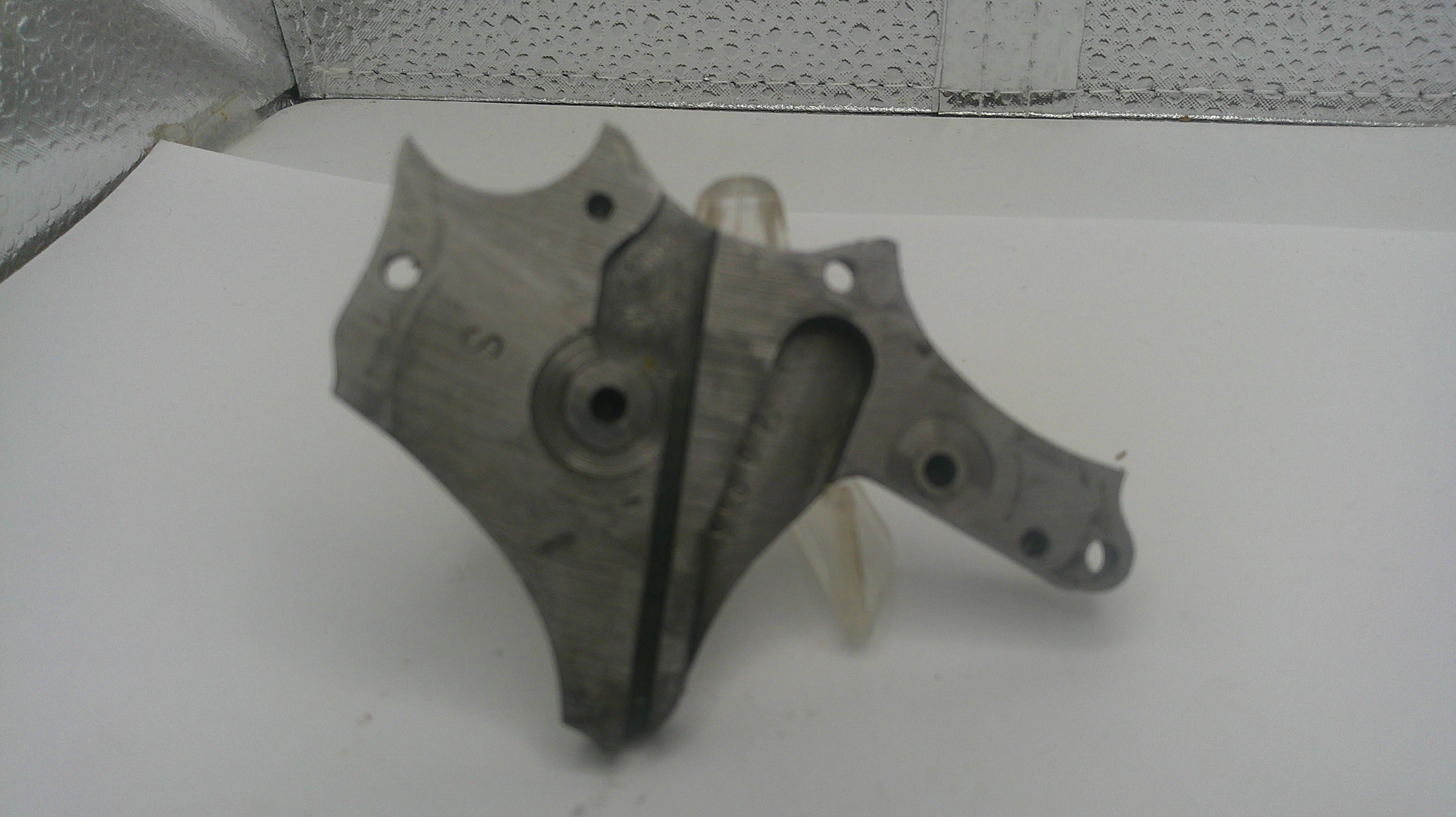 Metal mechanical part on a white surface with a speckled gray background