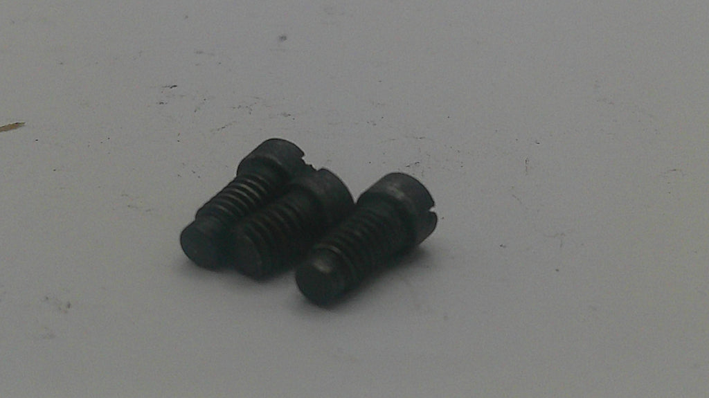 Three small black metal slotted screws on a plain light gray surface.
