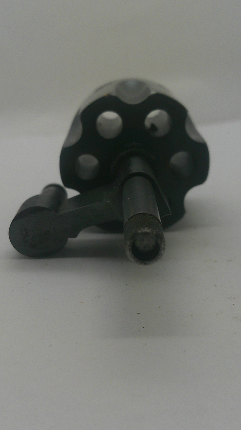 A close-up of a black metal wall hook with a textured, hammered finish, shown mounted on a plain white wall.