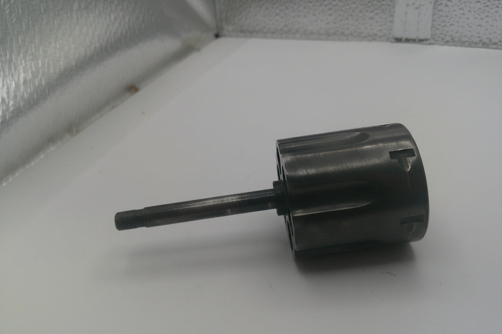Metal cylindrical object on a white surface with a textured background
