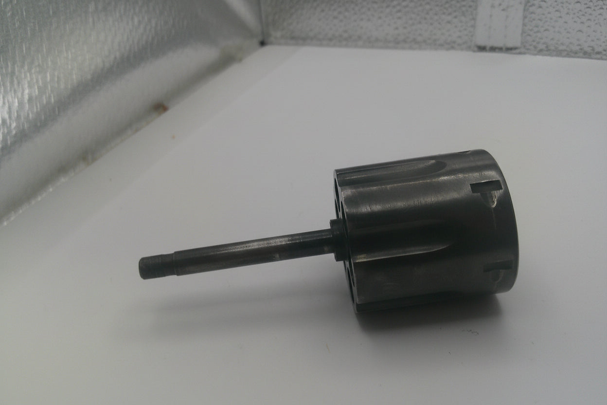 Metal cylindrical object on a white surface with a textured background