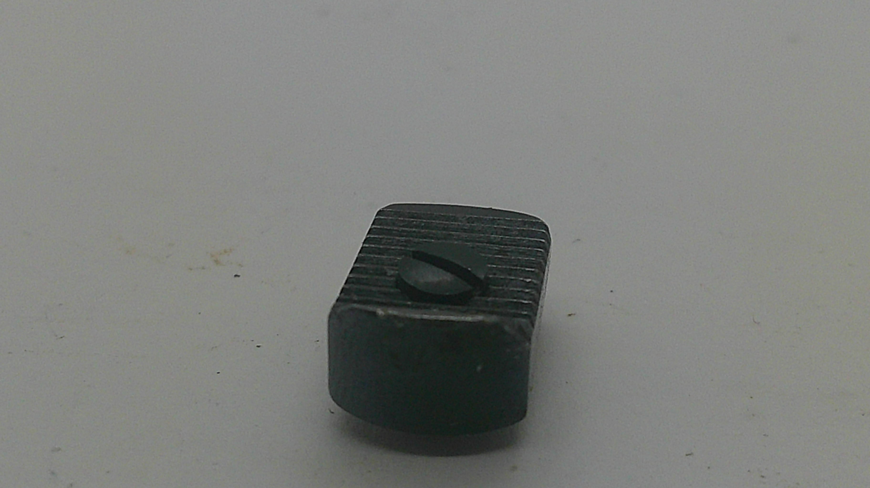 A small black rectangular plastic component with a ribbed top surface and a small oval cutout, shown on a plain light gray background.