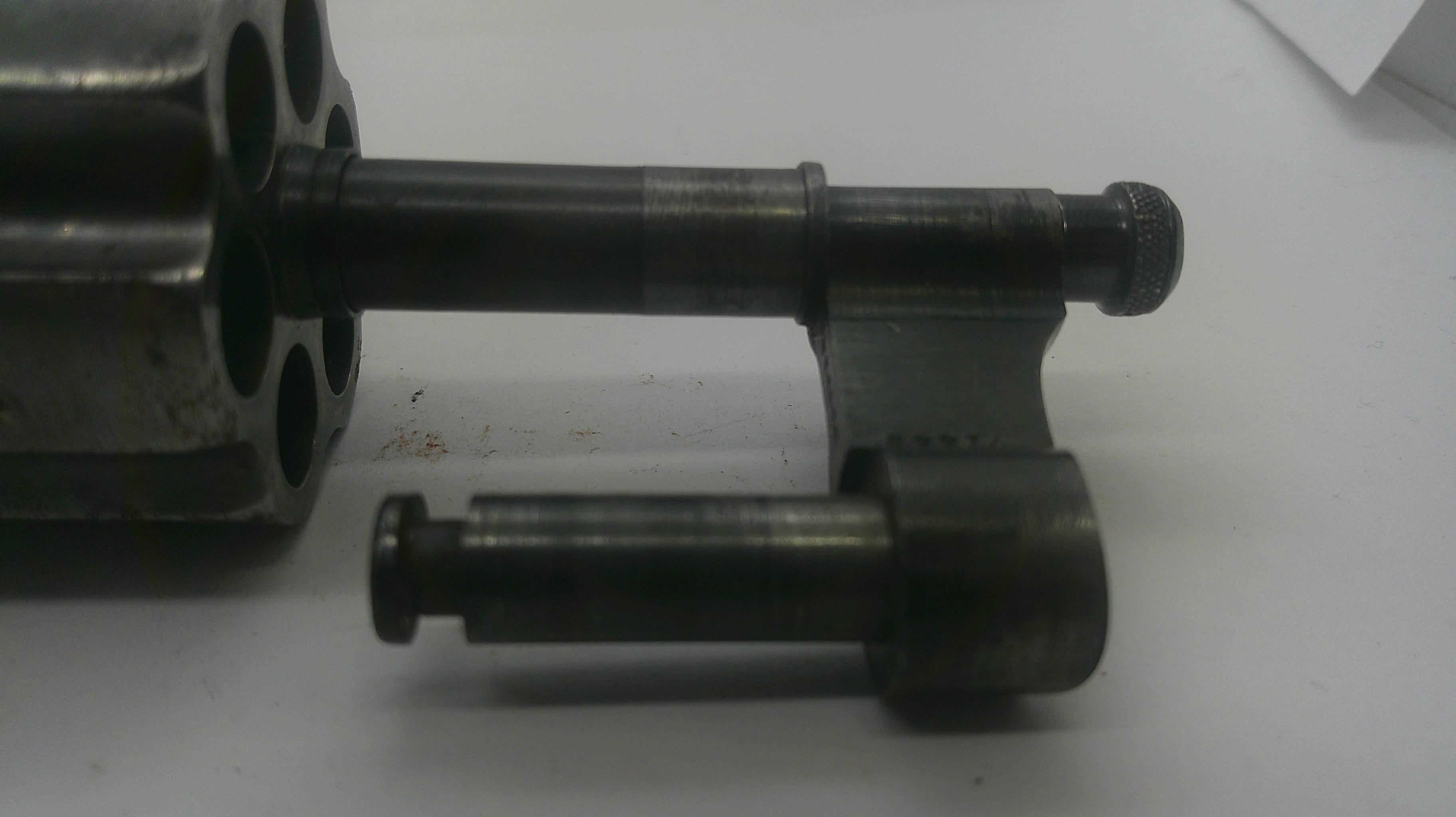 A close-up of a dark metallic mechanical component or tool part on a plain light background.