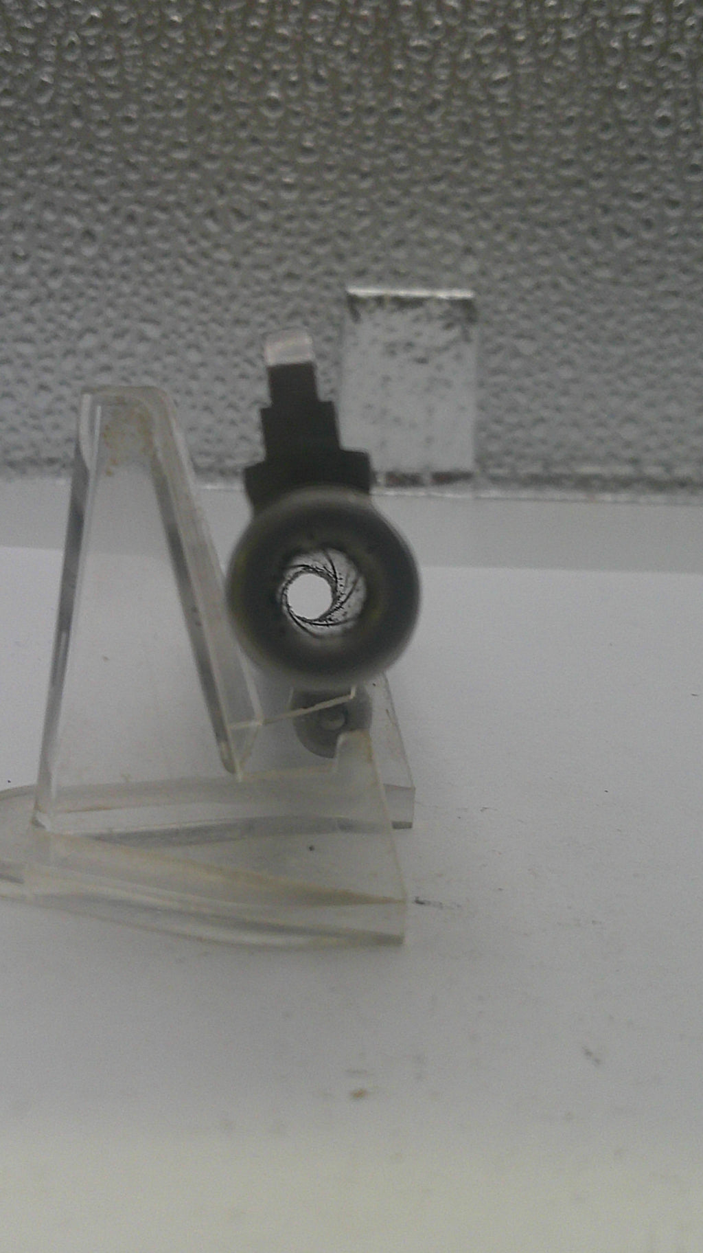 Small metal stand with a wheel on a textured surface