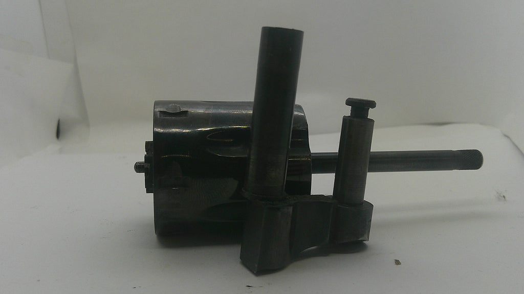 A dark metal mechanical part with a cylindrical body, vertical adjustment posts, and a long horizontal rod, photographed on a plain light background.