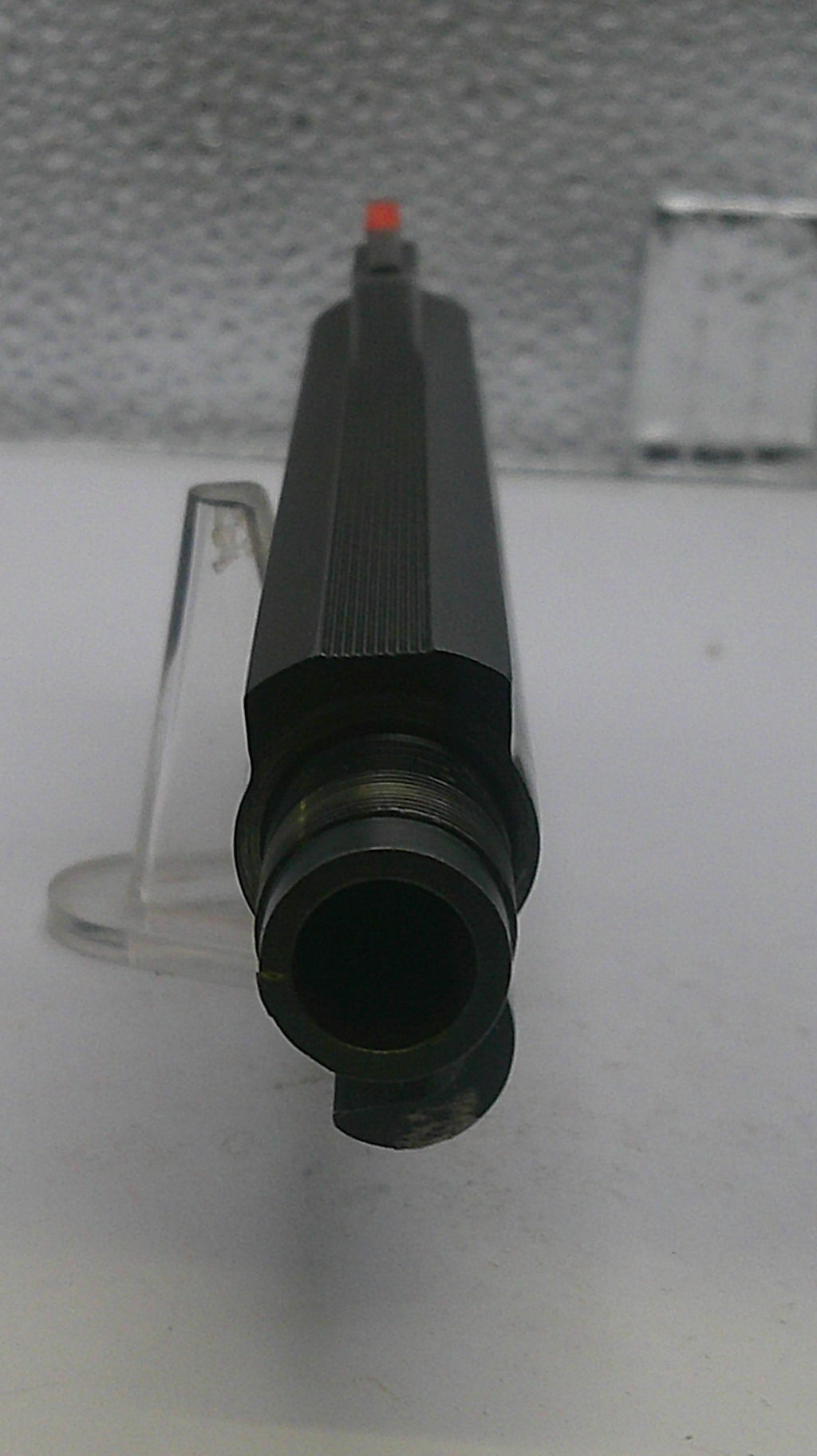 Black cylindrical object with a red tip on a white background