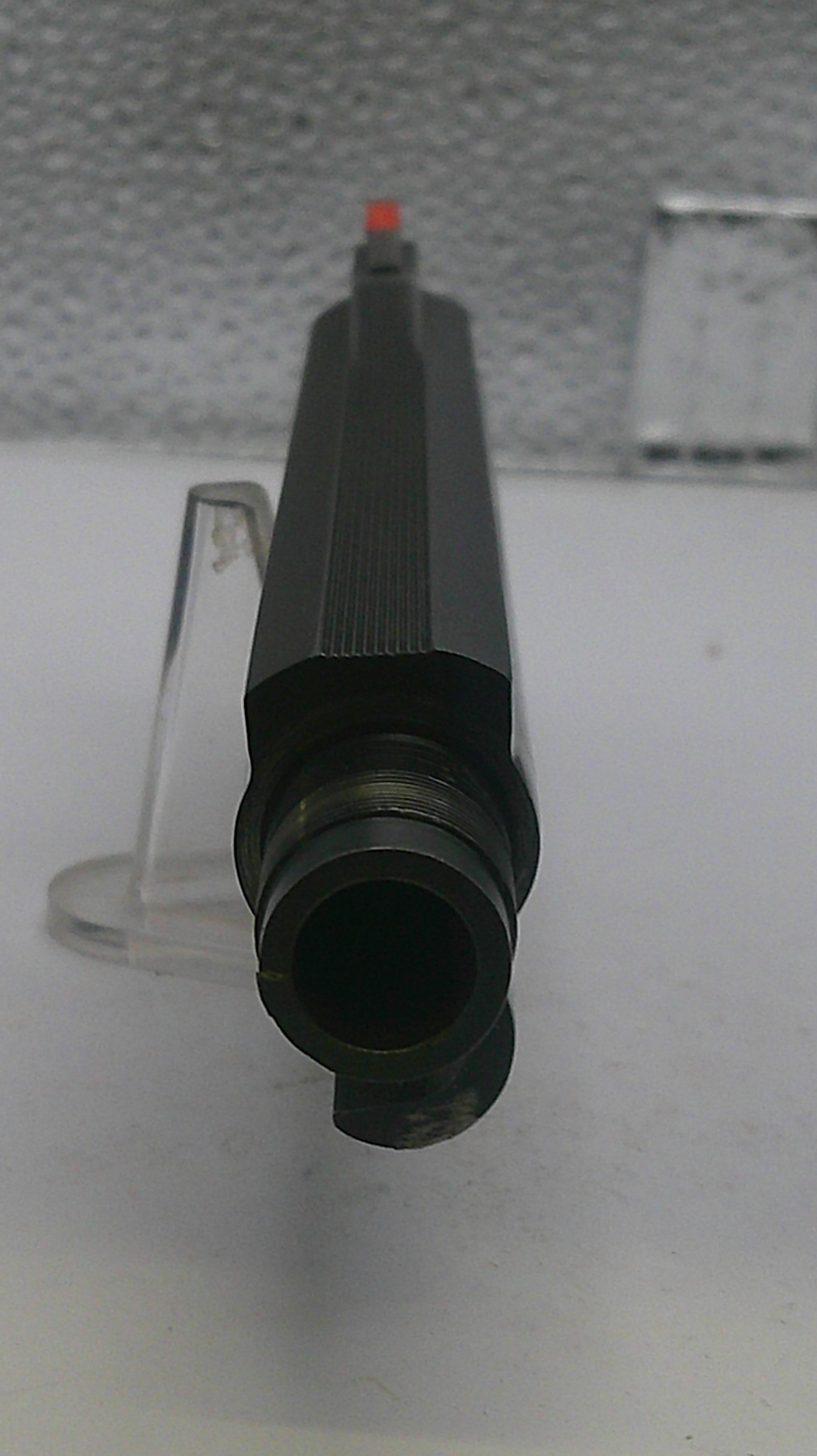Black cylindrical object with a red tip on a white background