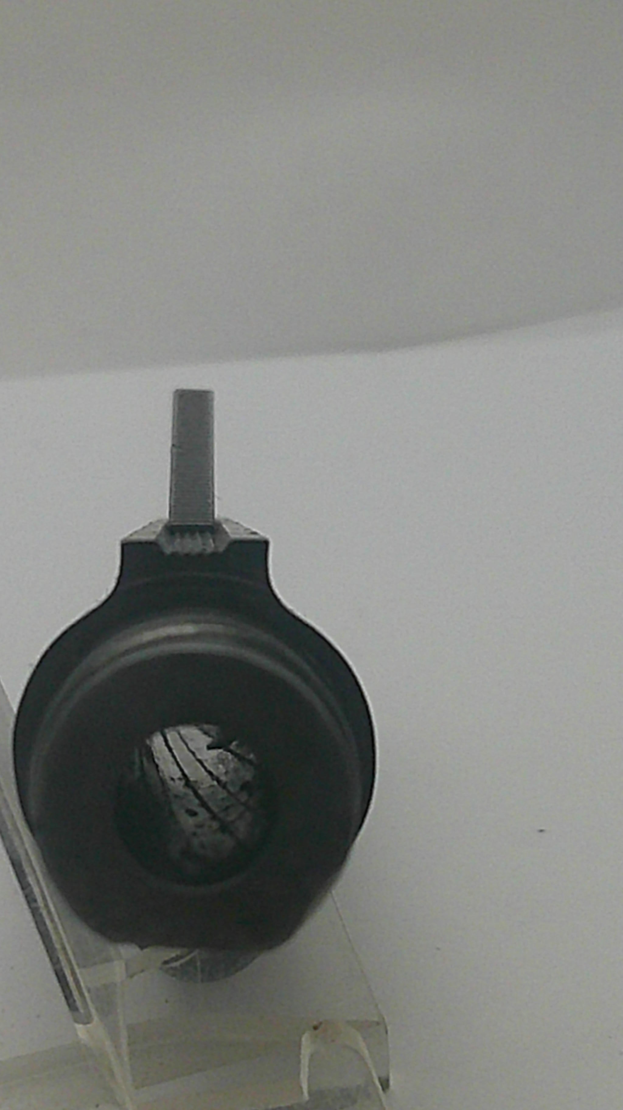 A close-up of a black circular component with a gray threaded rod or bolt extending from the side, mounted against a plain light background.