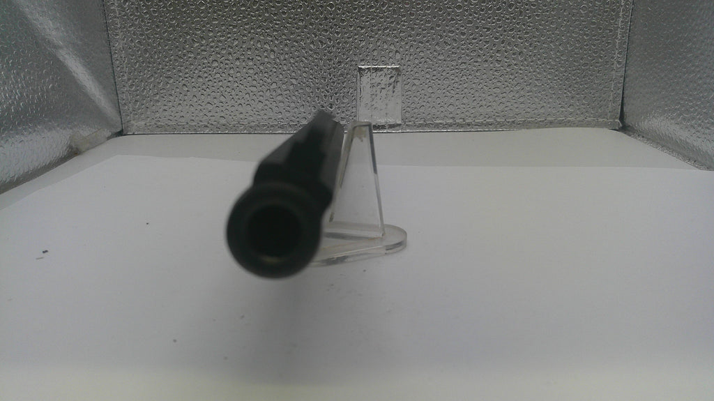 A close-up of a black cylindrical object, possibly a tool or accessory, resting on a clear plastic stand against a textured silver background.