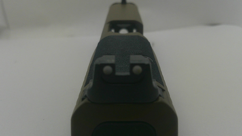Close-up of the rear sight area of a rifle stock in matte black and dark olive green, photographed against a plain white background.