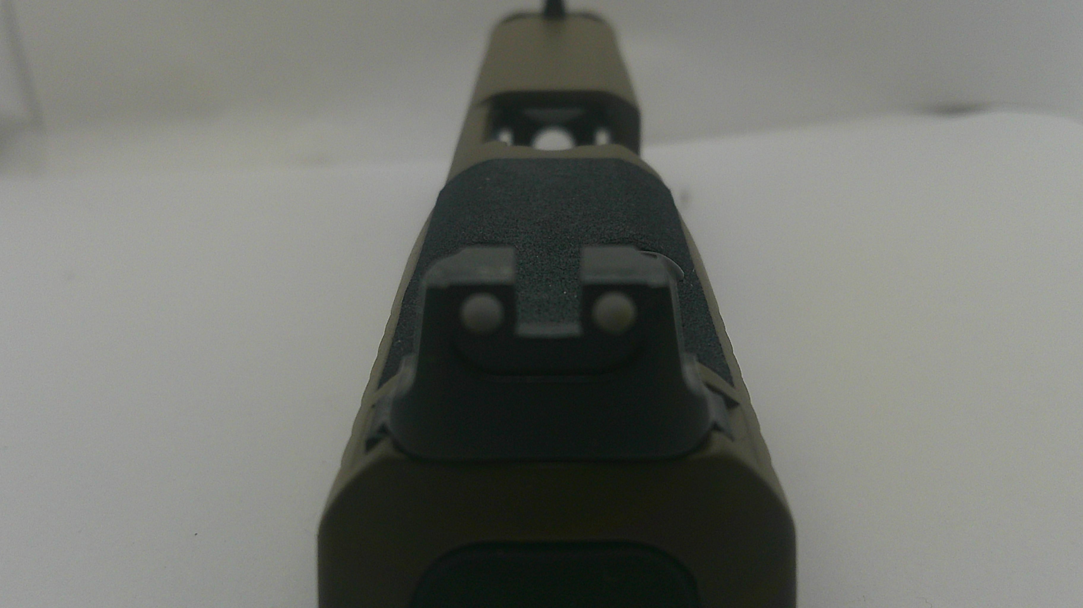 Close-up of the rear sight area of a rifle stock in matte black and dark olive green, photographed against a plain white background.