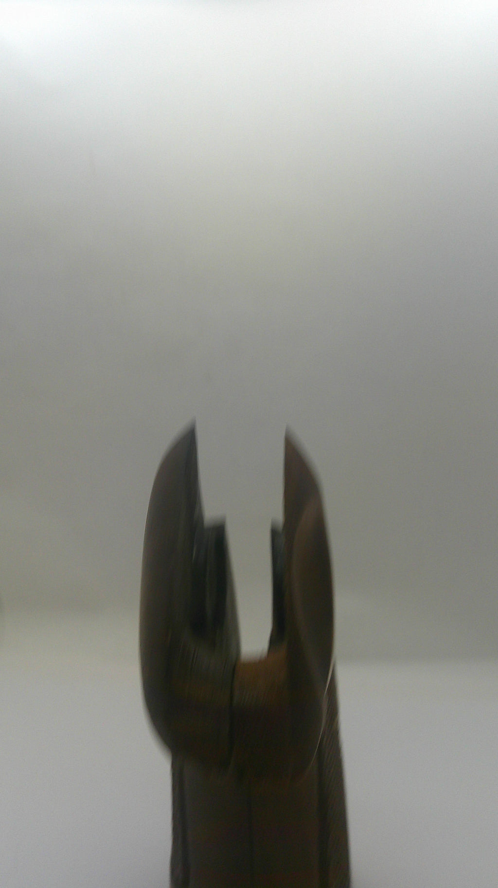 A close-up of a dark brown wooden tool or handle with a curved, claw-like end, shown against a plain light gray background.