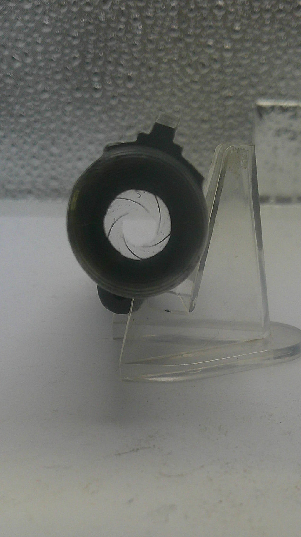 Clear plastic stand with a black circular object on a white background