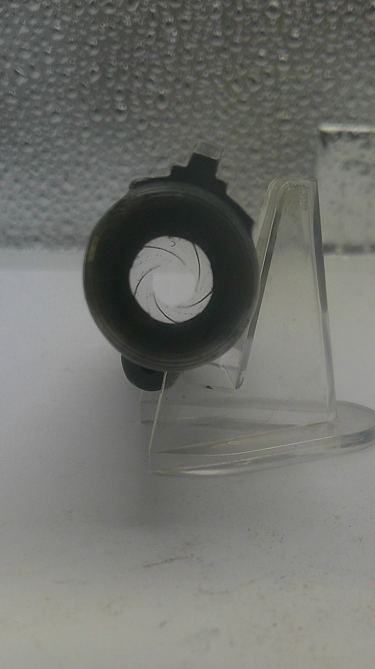 Clear plastic stand with a black circular object on a white background