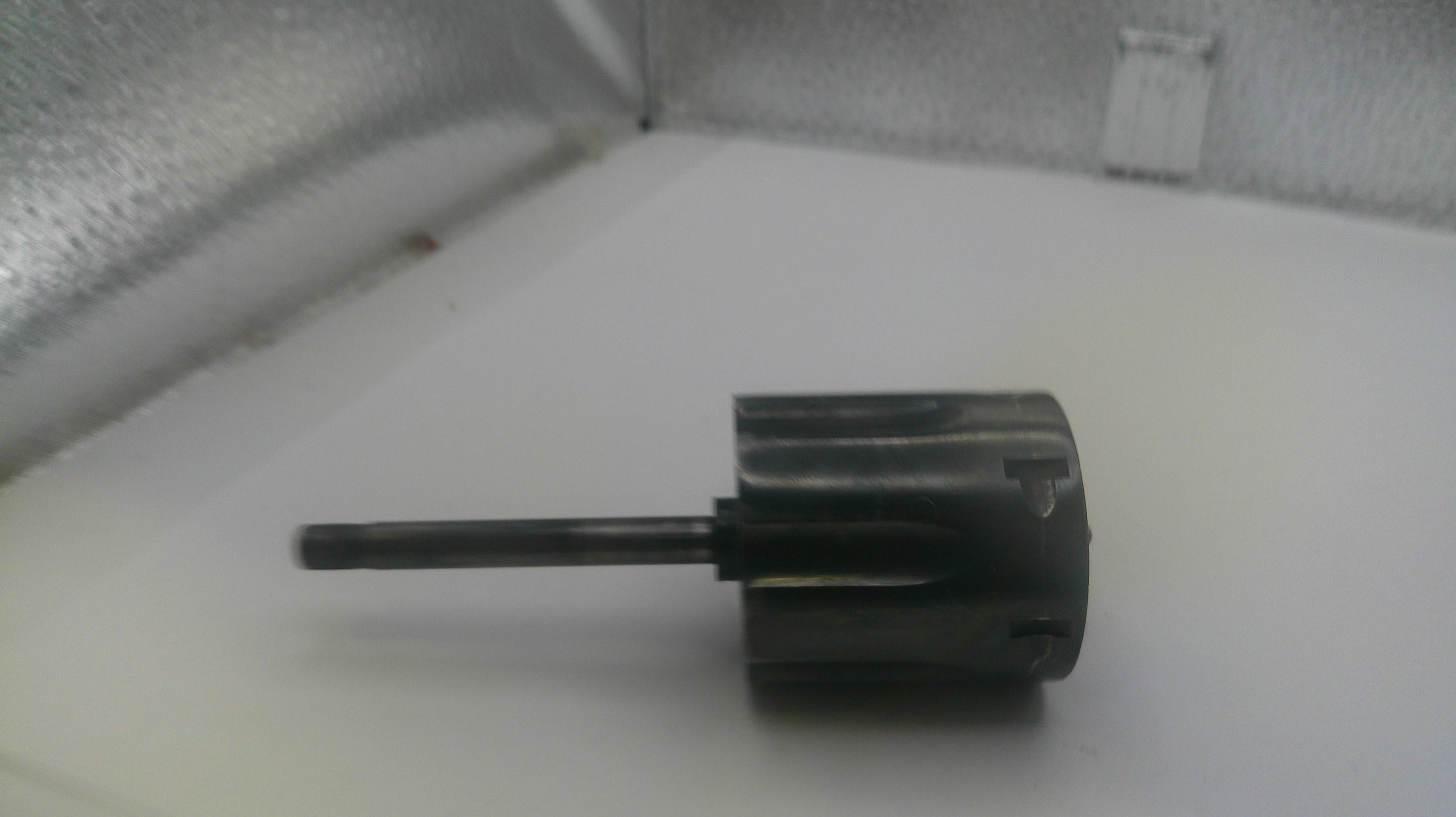 Black cylindrical object with a long shaft on a white surface