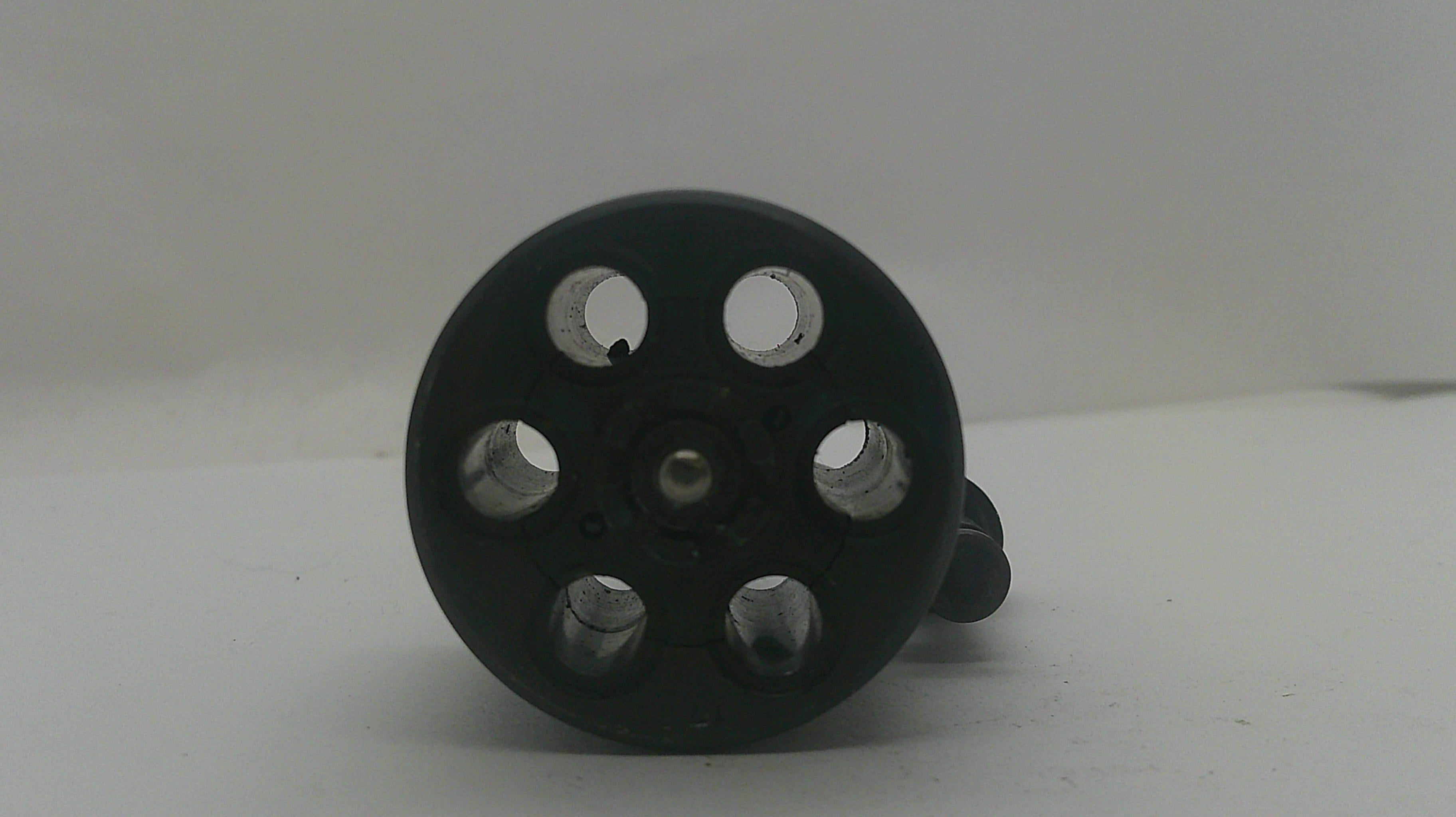 A black plastic six-hole suppressor or muzzle device with circular cutouts, shown on a plain light gray background.