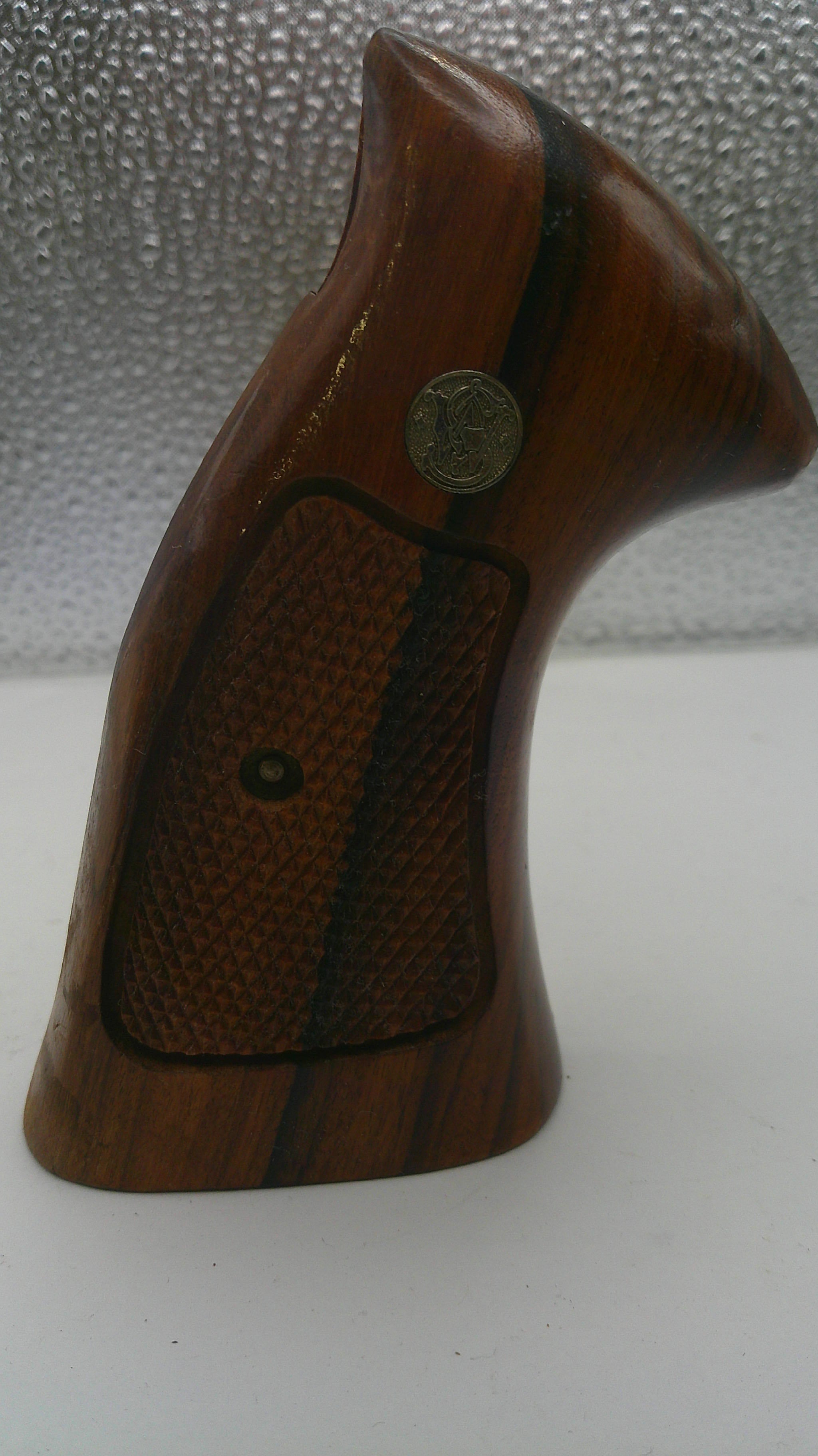 Wooden gun grip with text on a textured surface