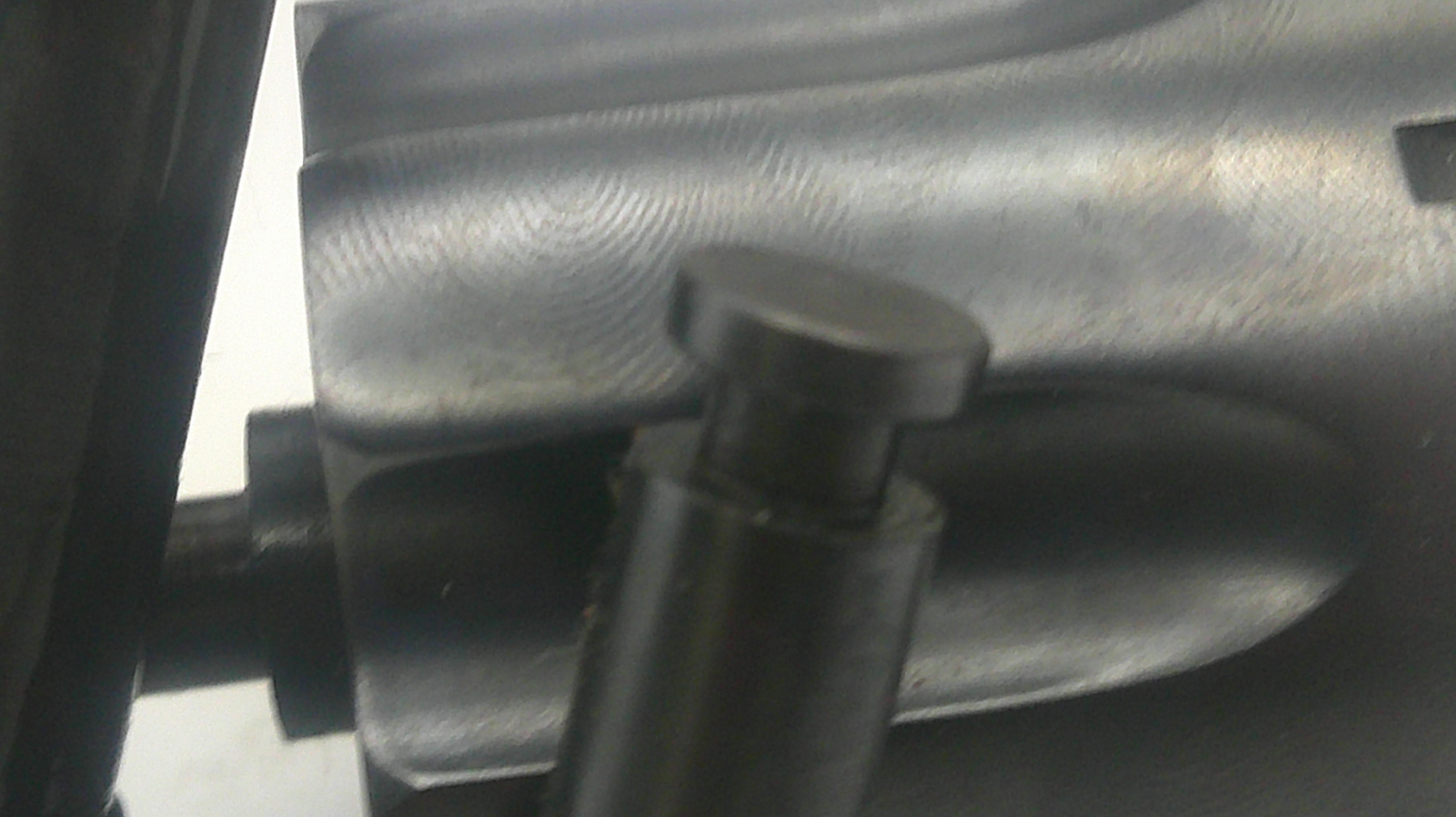 Close-up of a black metal chair leg with a round adjustment knob, attached to a black metal frame.