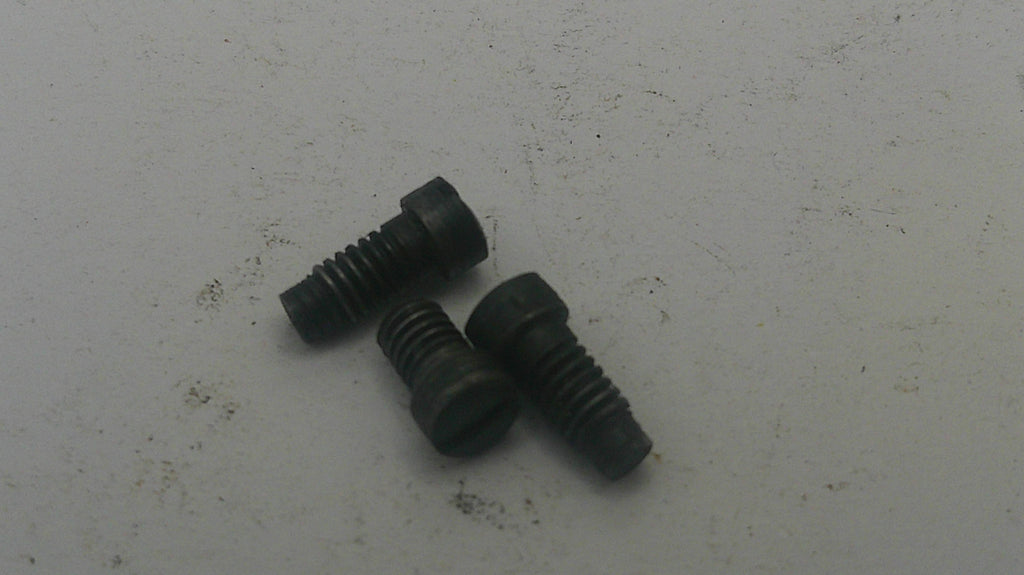 Three black screws on a white surface with visible dirt.