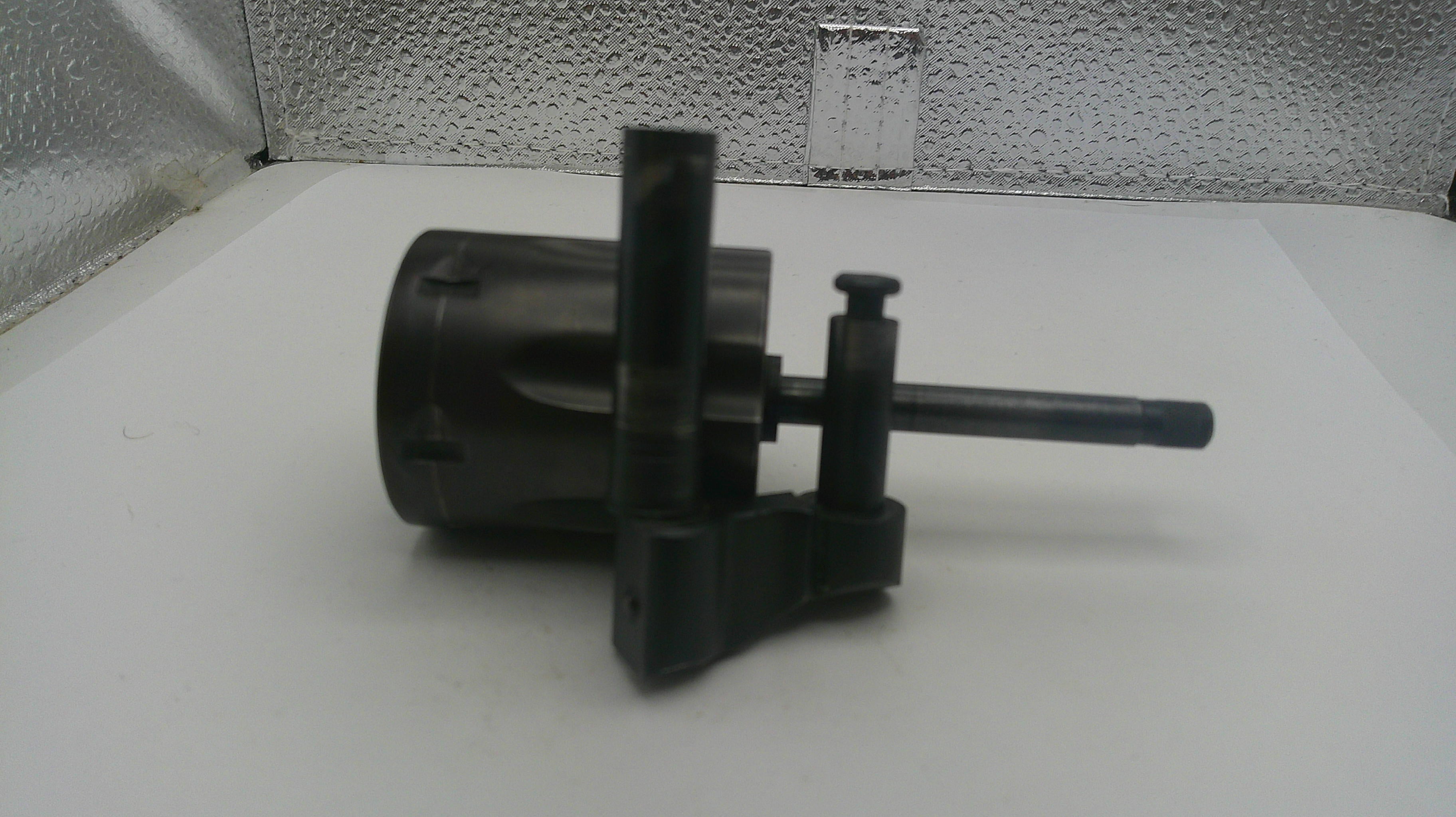 Black mechanical component on a white surface with a textured wall background