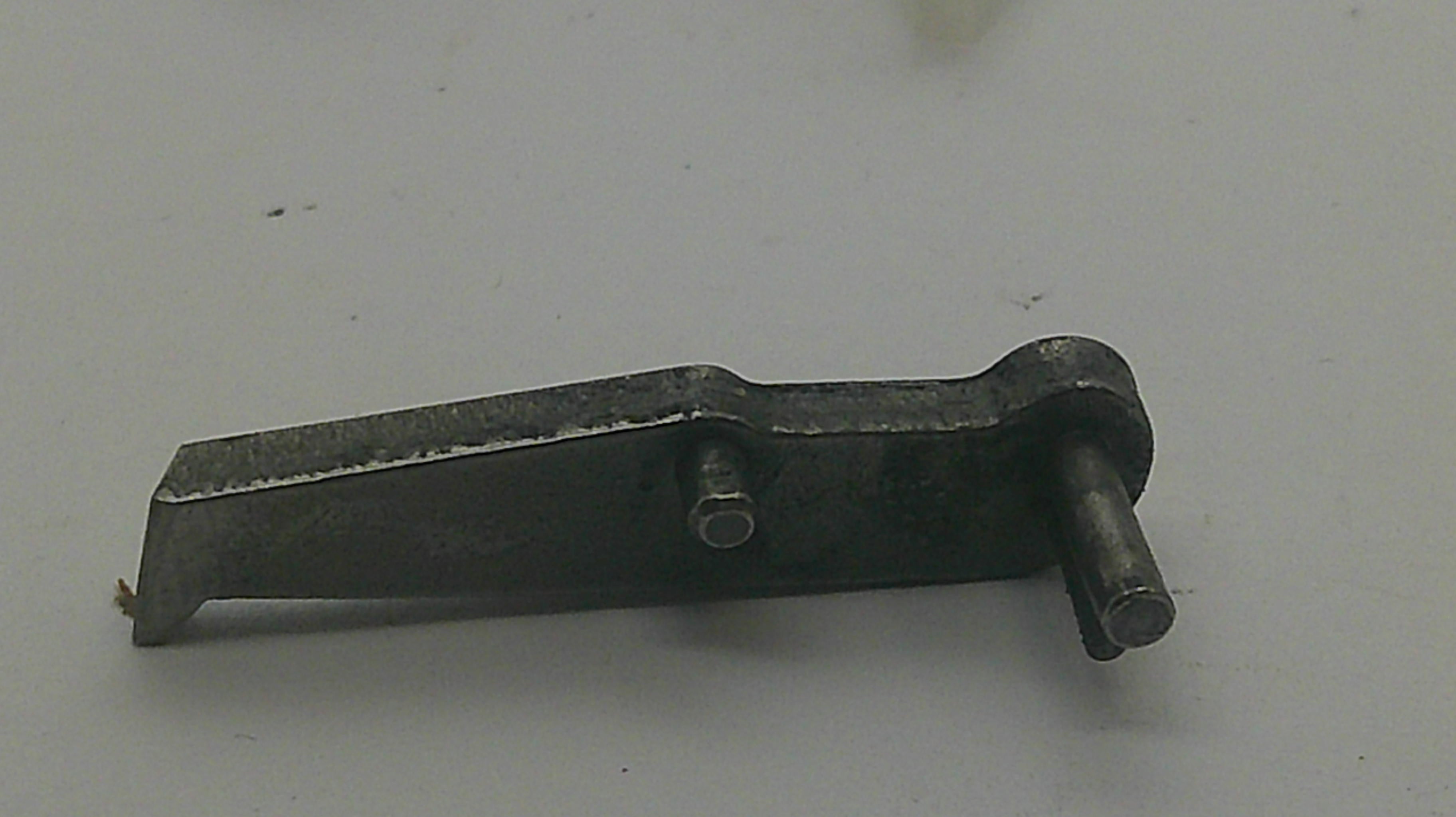 A small dark metal hardware component with a flat rectangular plate, a bolt hole, and a cylindrical pin, photographed on a plain light background.